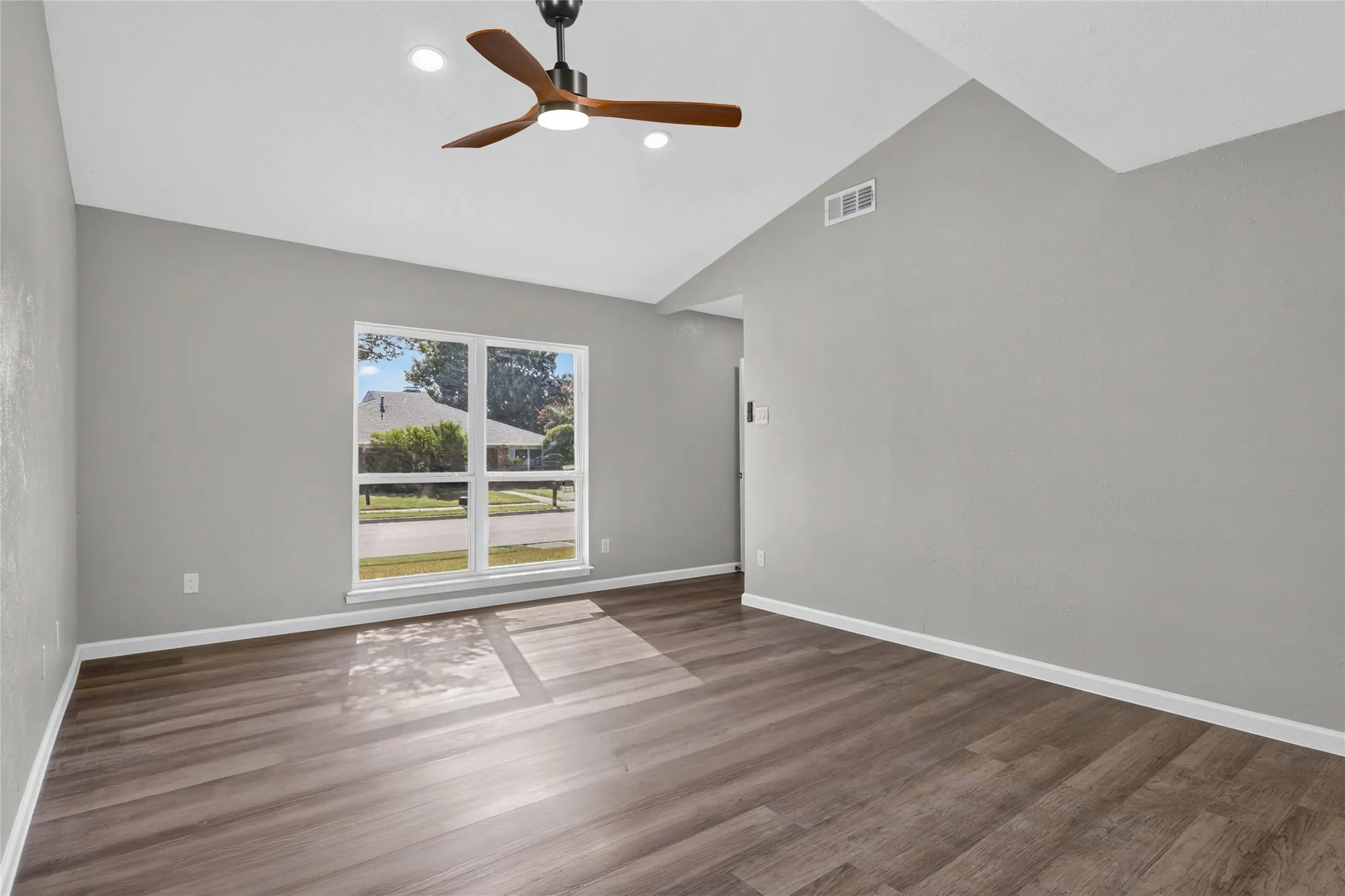 Vaulted ceiling with a contemporary ceiling fan, recessed lighting, wood-finish flooring, and a large window