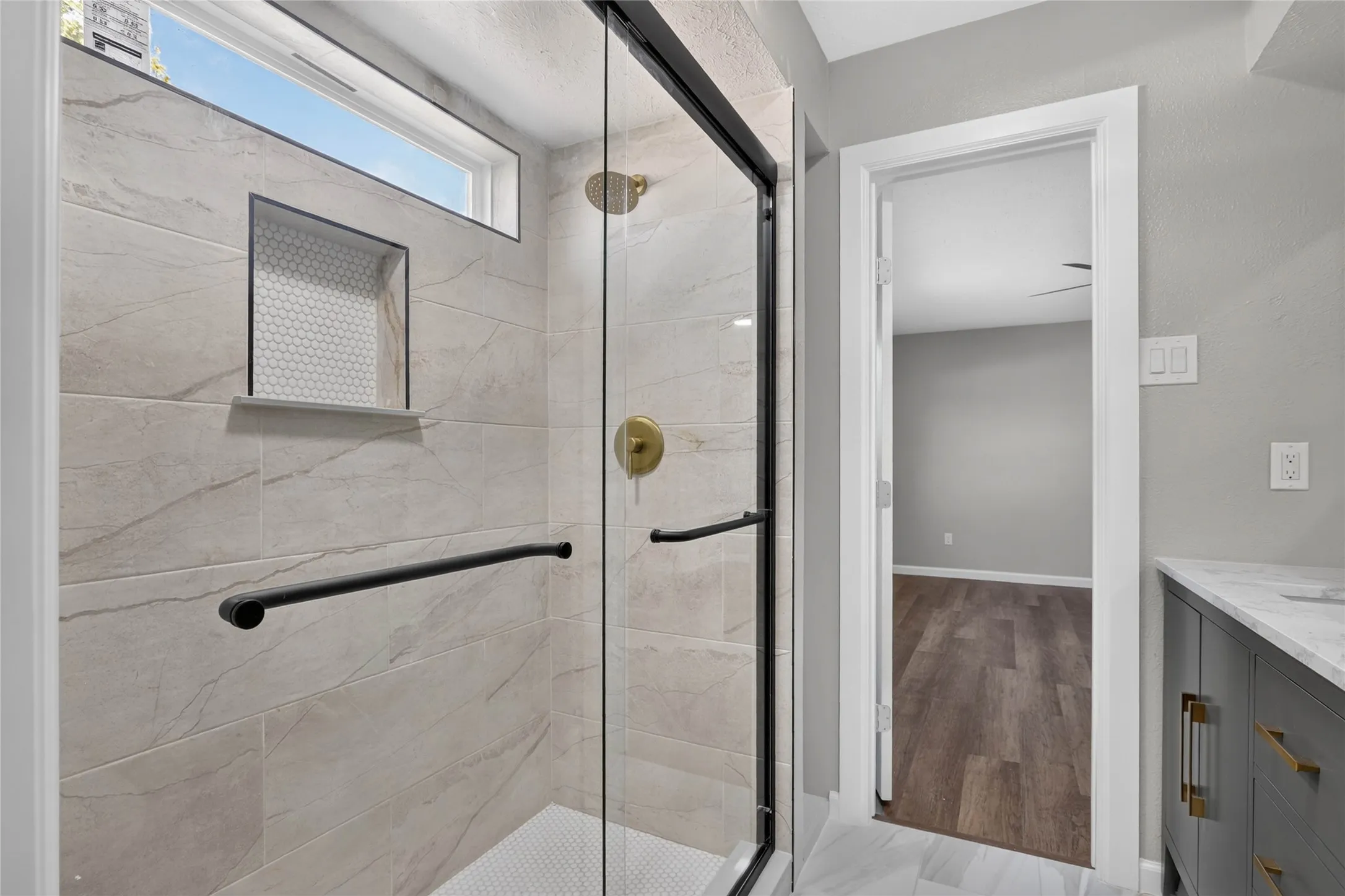 Glass-enclosed shower with a transom window, built-in tiled niche, and a gold-finish shower head