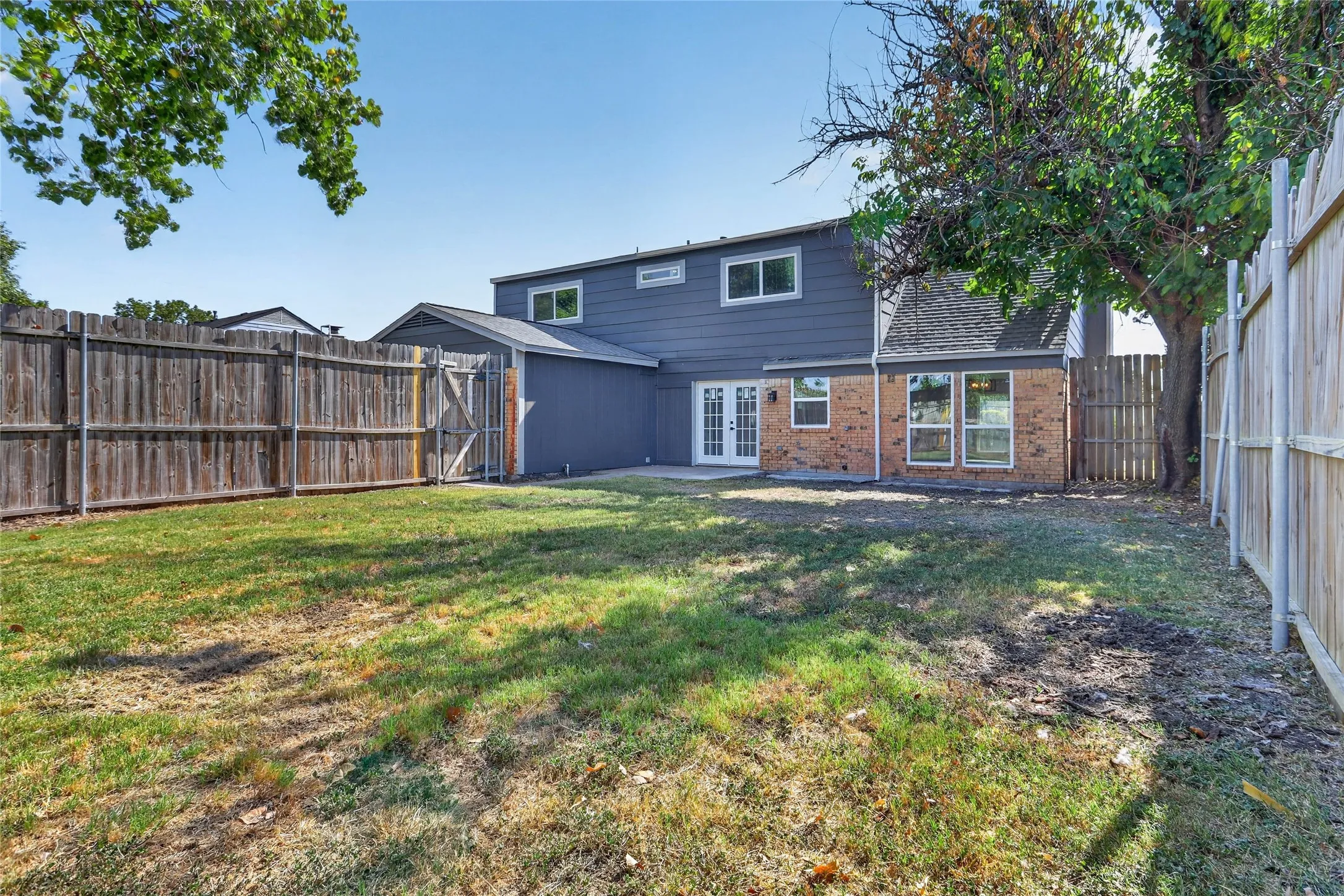 Fenced backyard featuring a two-story home with brick and siding facade