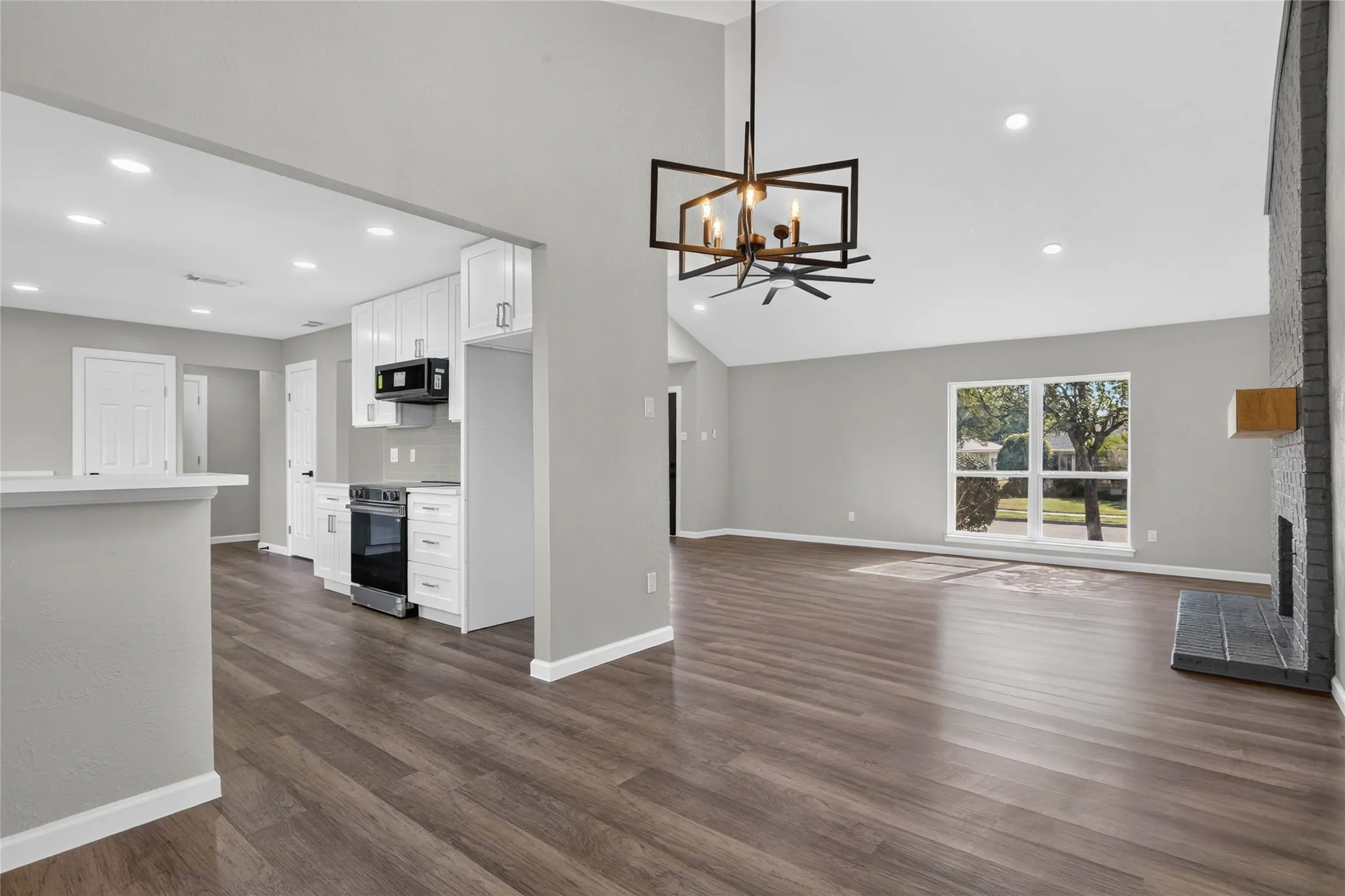 Vaulted ceilings with recessed lighting, wood-finish flooring, and a modern chandelier