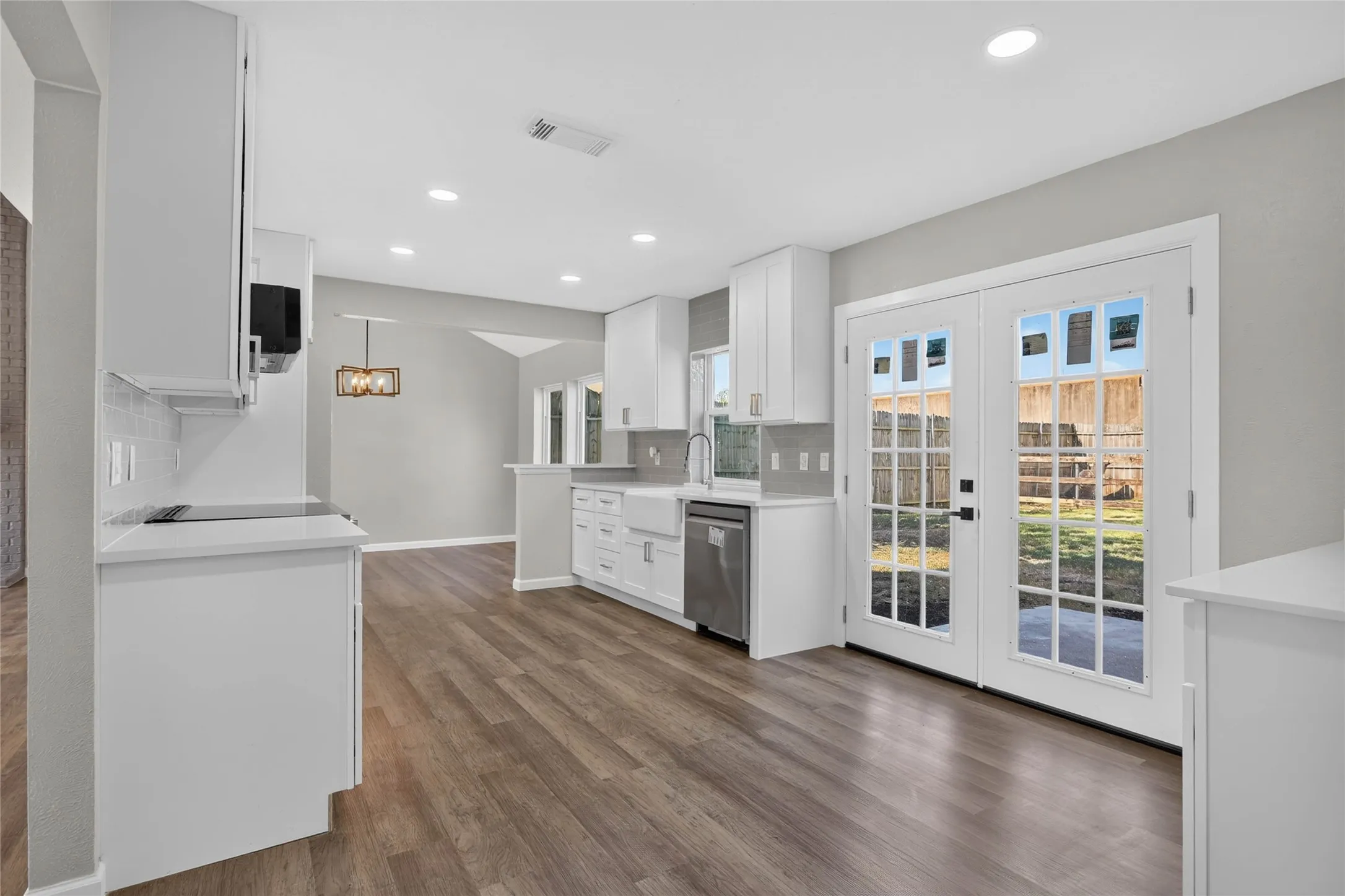Modern kitchen featuring white cabinetry, light countertops, wood-finish flooring, recessed lighting, and double glass-panel doors