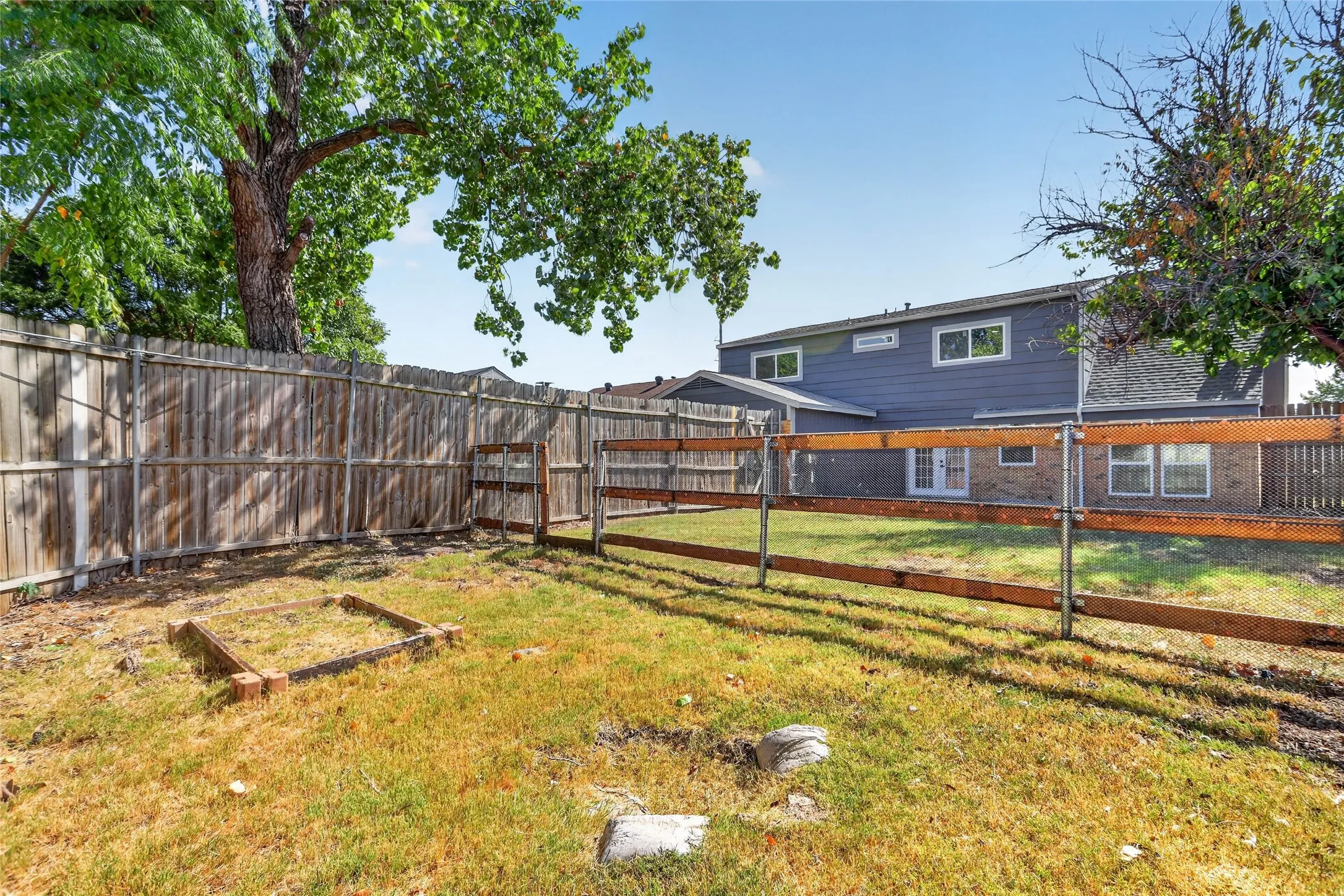 Expansive backyard featuring a wood privacy fence, a wood-rail fence, and mature trees