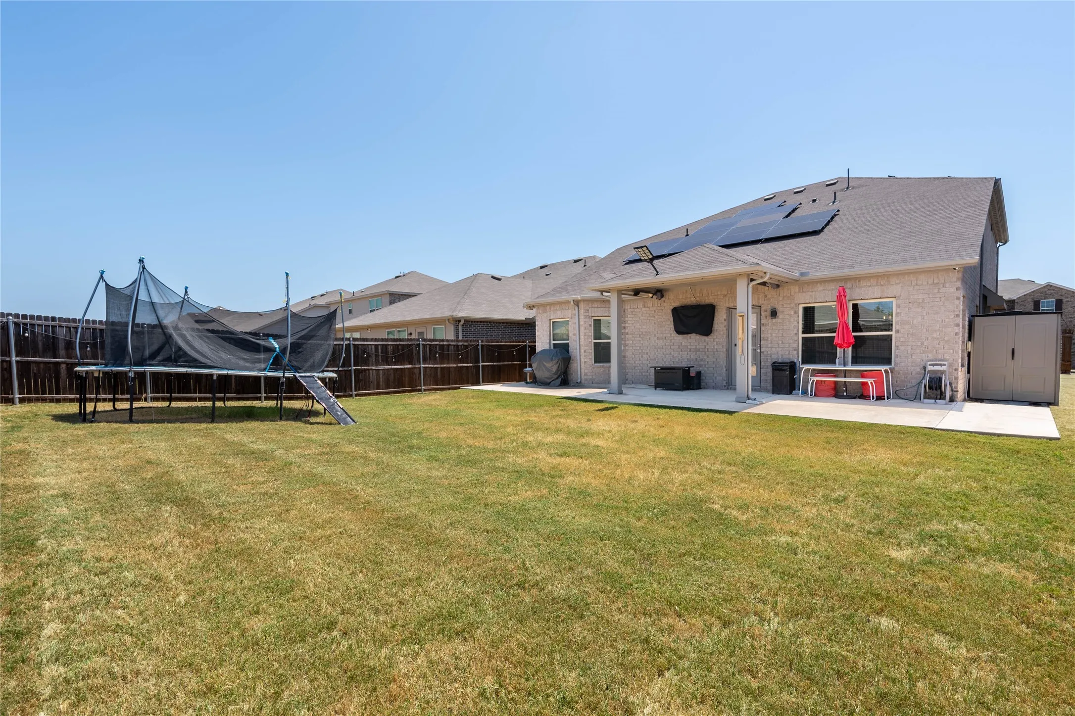Expansive backyard with a full privacy fence, covered patio, and concrete slab