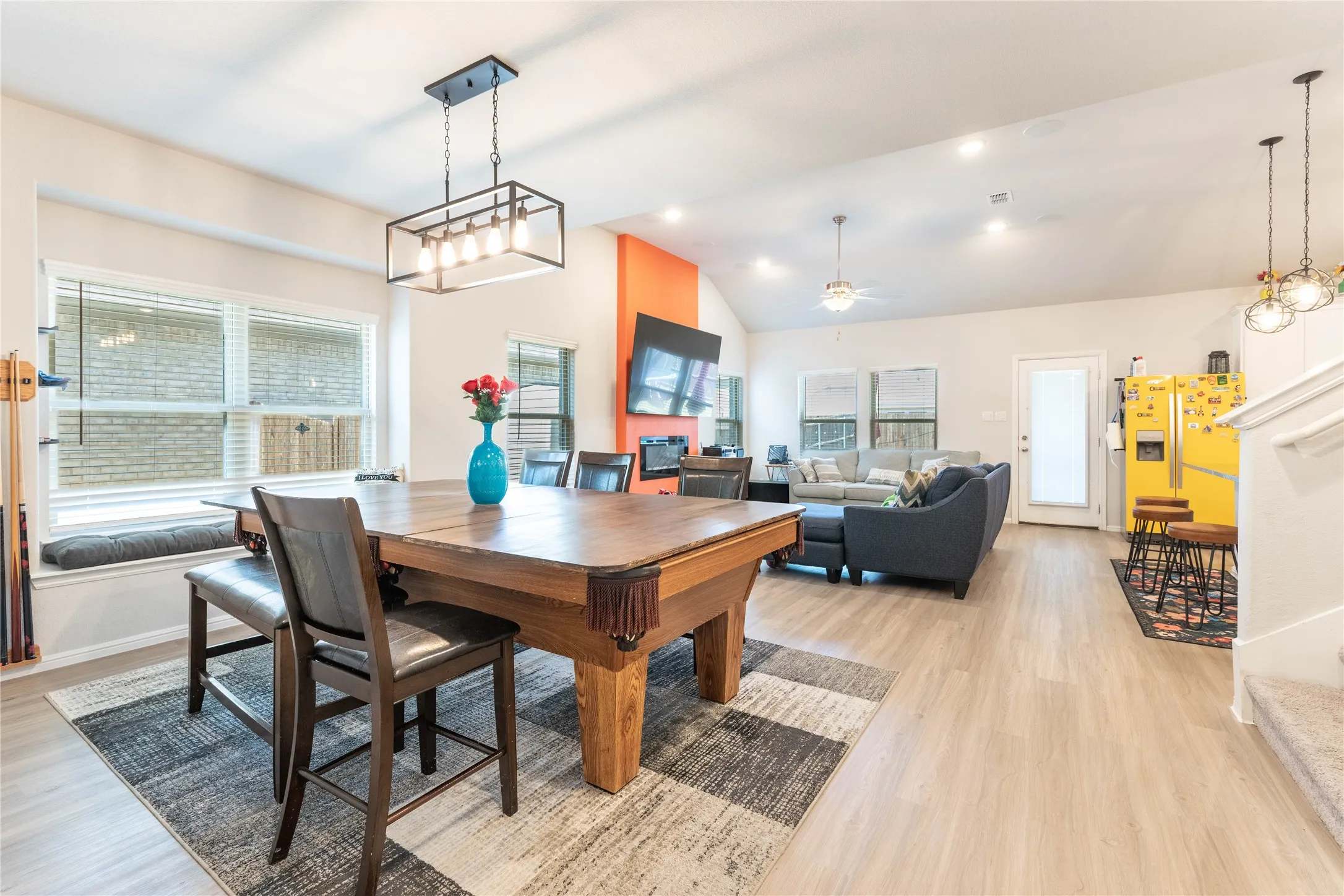 Open-concept living space with wood-finish flooring, vaulted ceiling, and recessed lighting