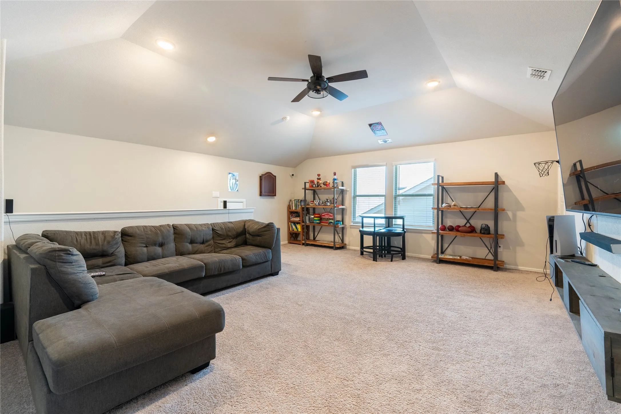 Carpeted loft area with vaulted ceilings, recessed lighting, ceiling fan, and multiple windows