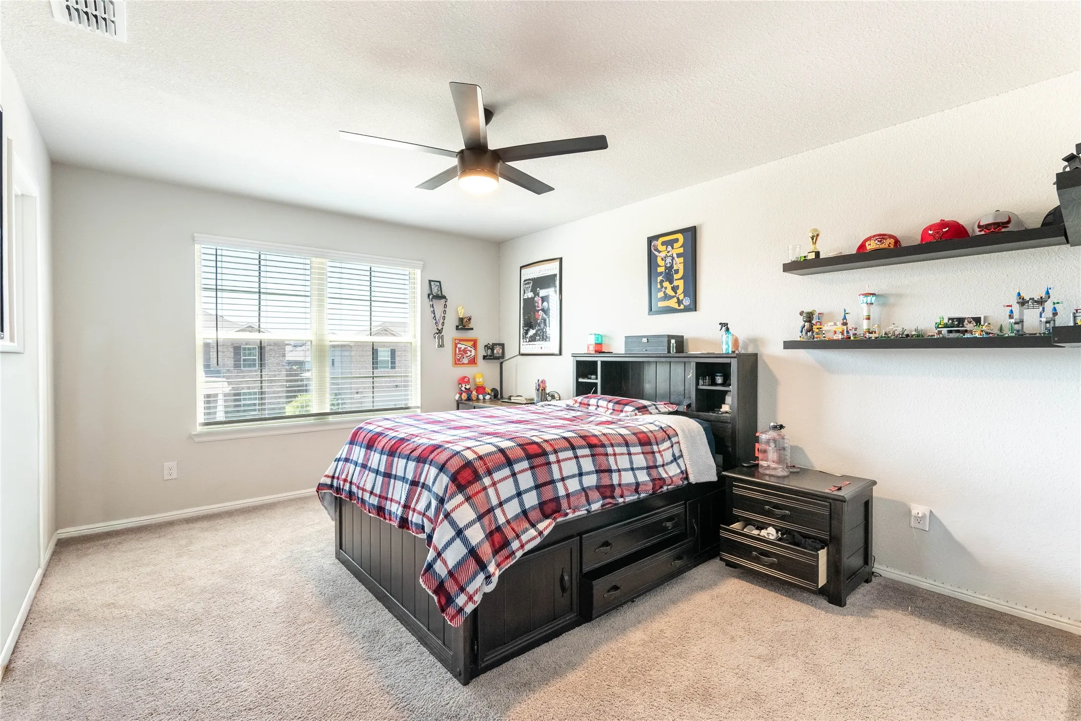 Carpeted room with a large window, ceiling fan, and light-toned walls