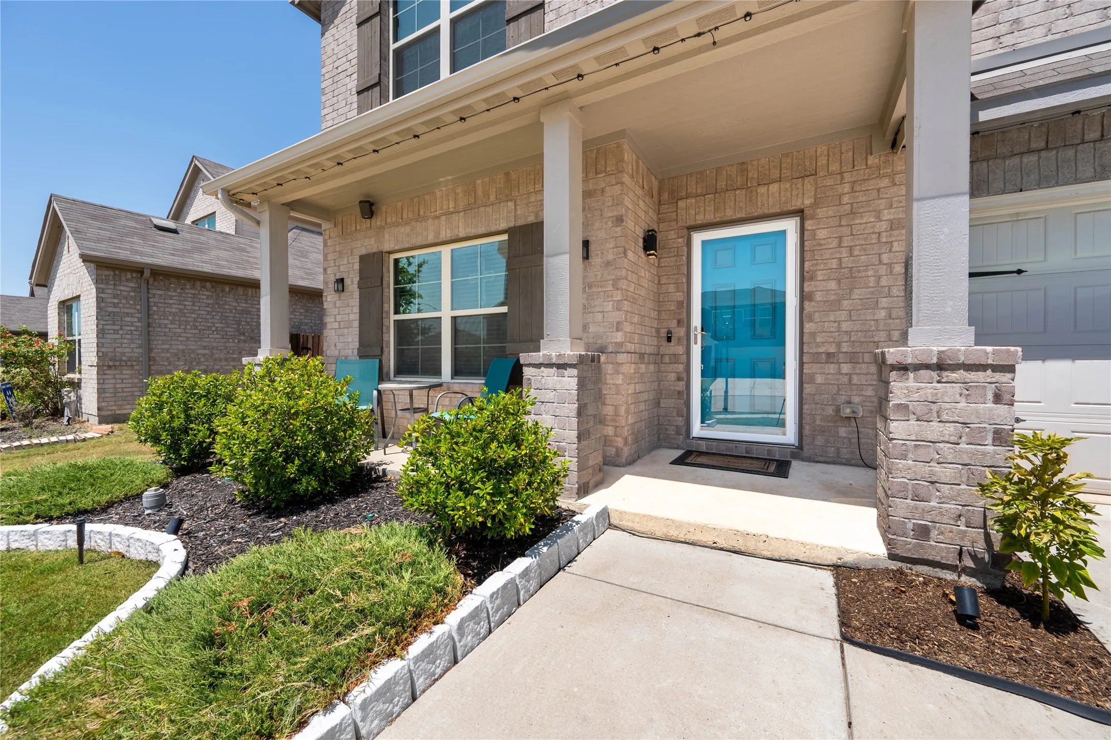 Brick exterior with a covered porch, decorative shutters, and mature landscaping