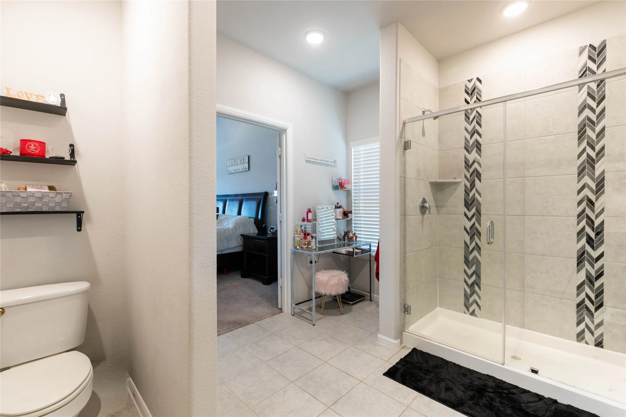 Walk-in shower with clear glass enclosure and chevron-patterned tile accents