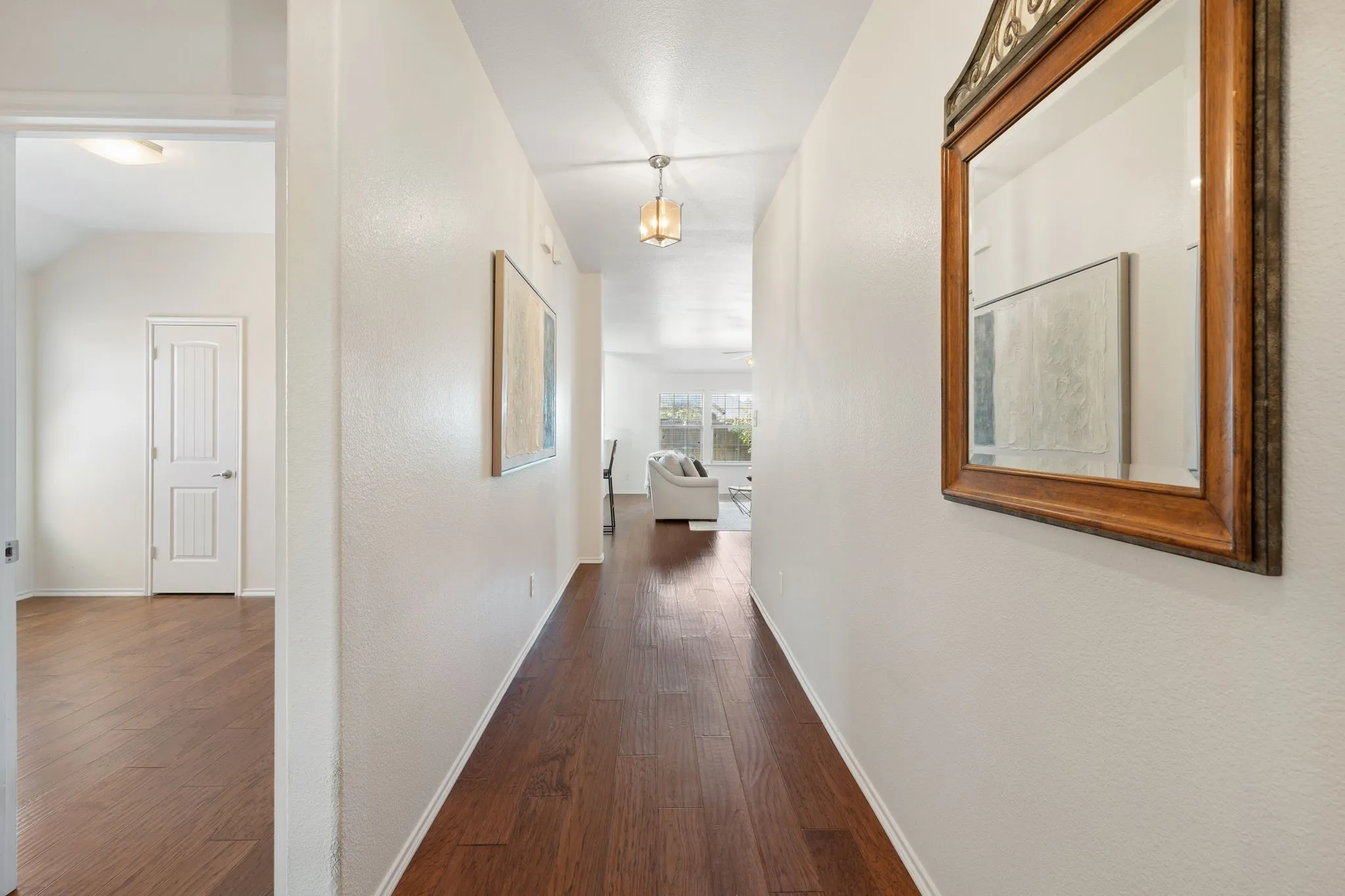 Wood-finish flooring throughout, white painted walls, and overhead lighting fixtures
