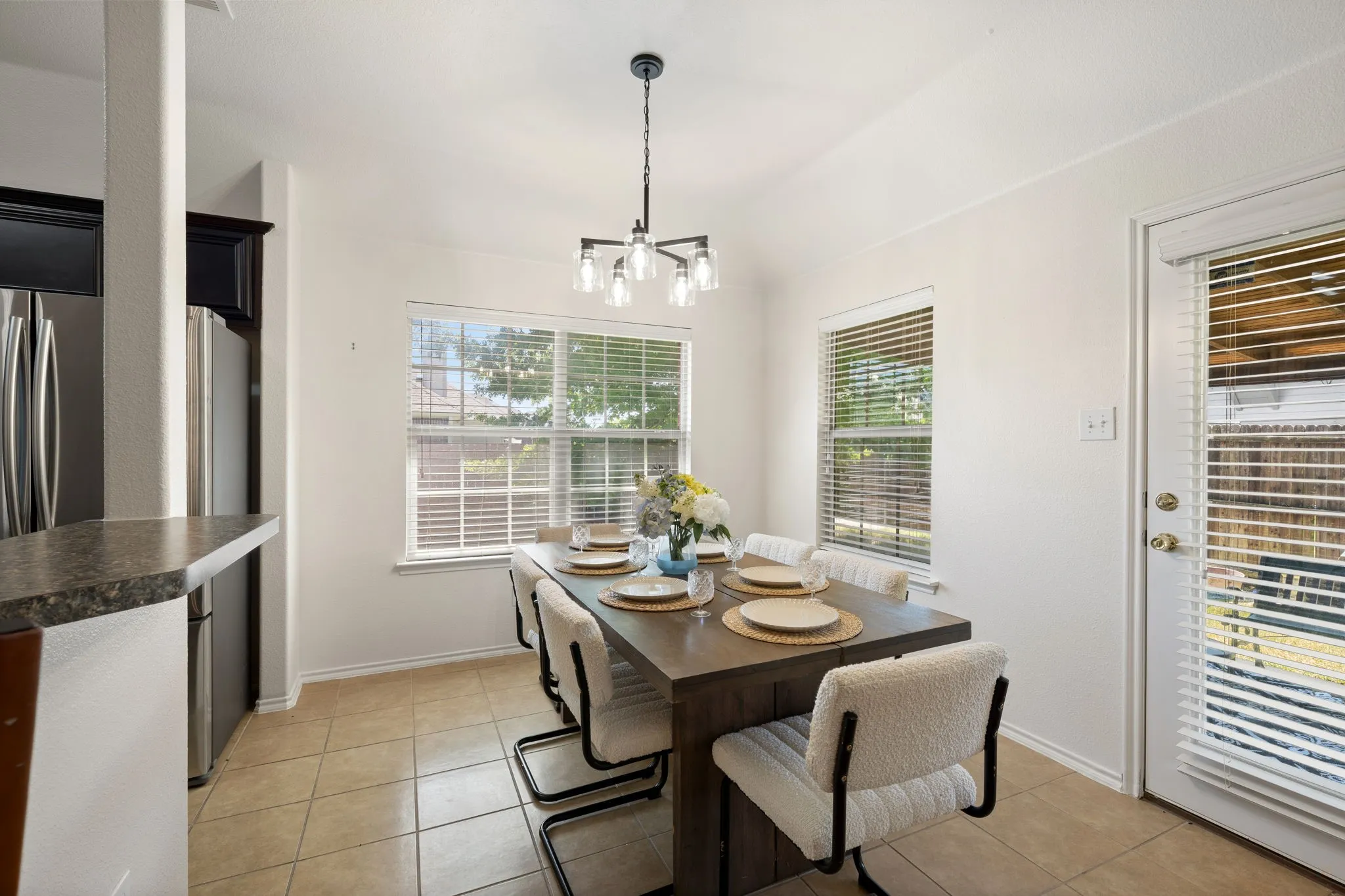 Recessed lighting, tile flooring, two windows with blinds, a glass-paneled door with blinds, and a built-in breakfast bar