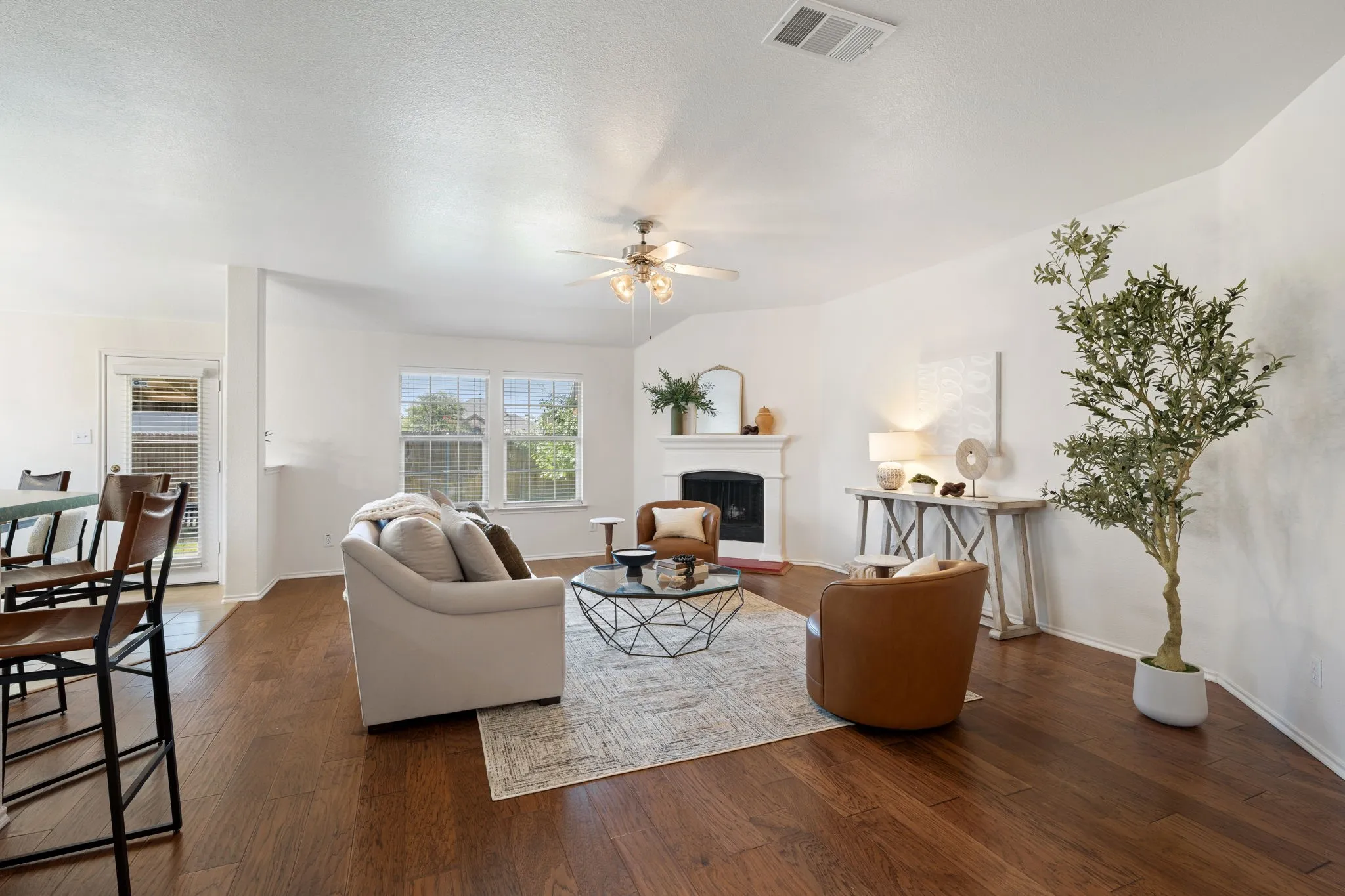 Living area featuring dark wood-finish flooring, white walls, and a ceiling fan