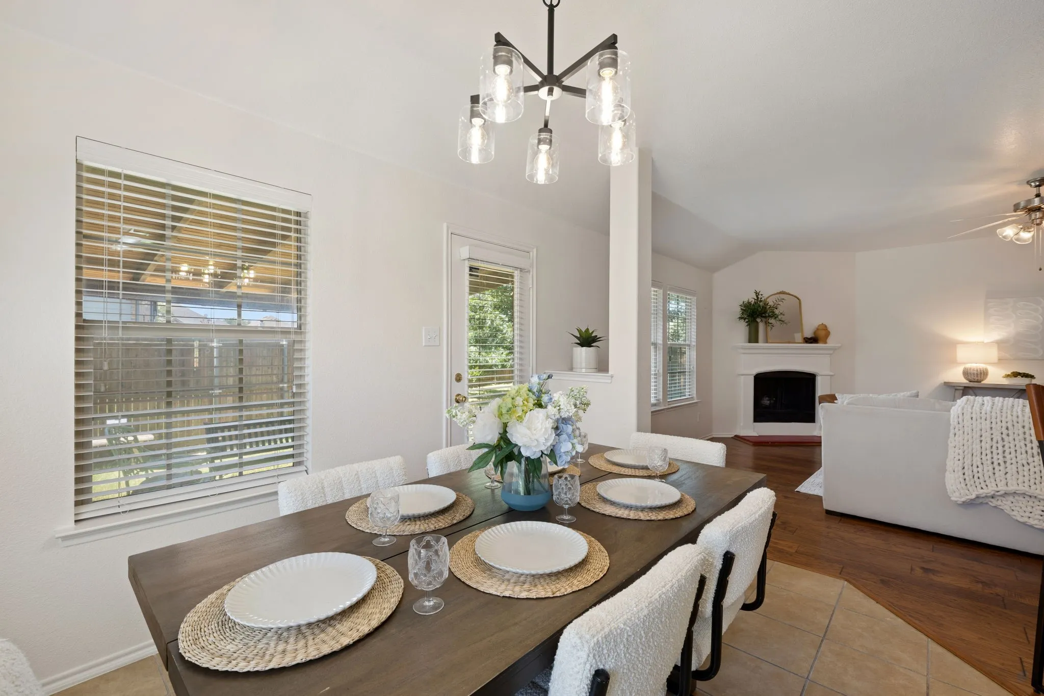 Modern chandelier over a wood-finish dining table with tile flooring