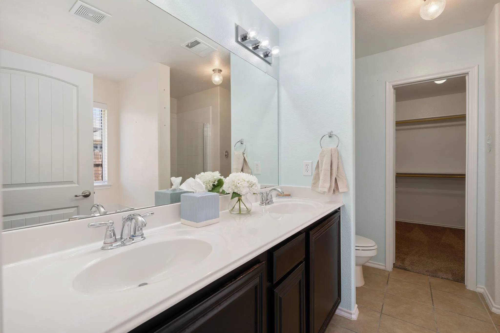 Dual vanity with integrated sinks, dark wood-finish cabinetry, and chrome fixtures