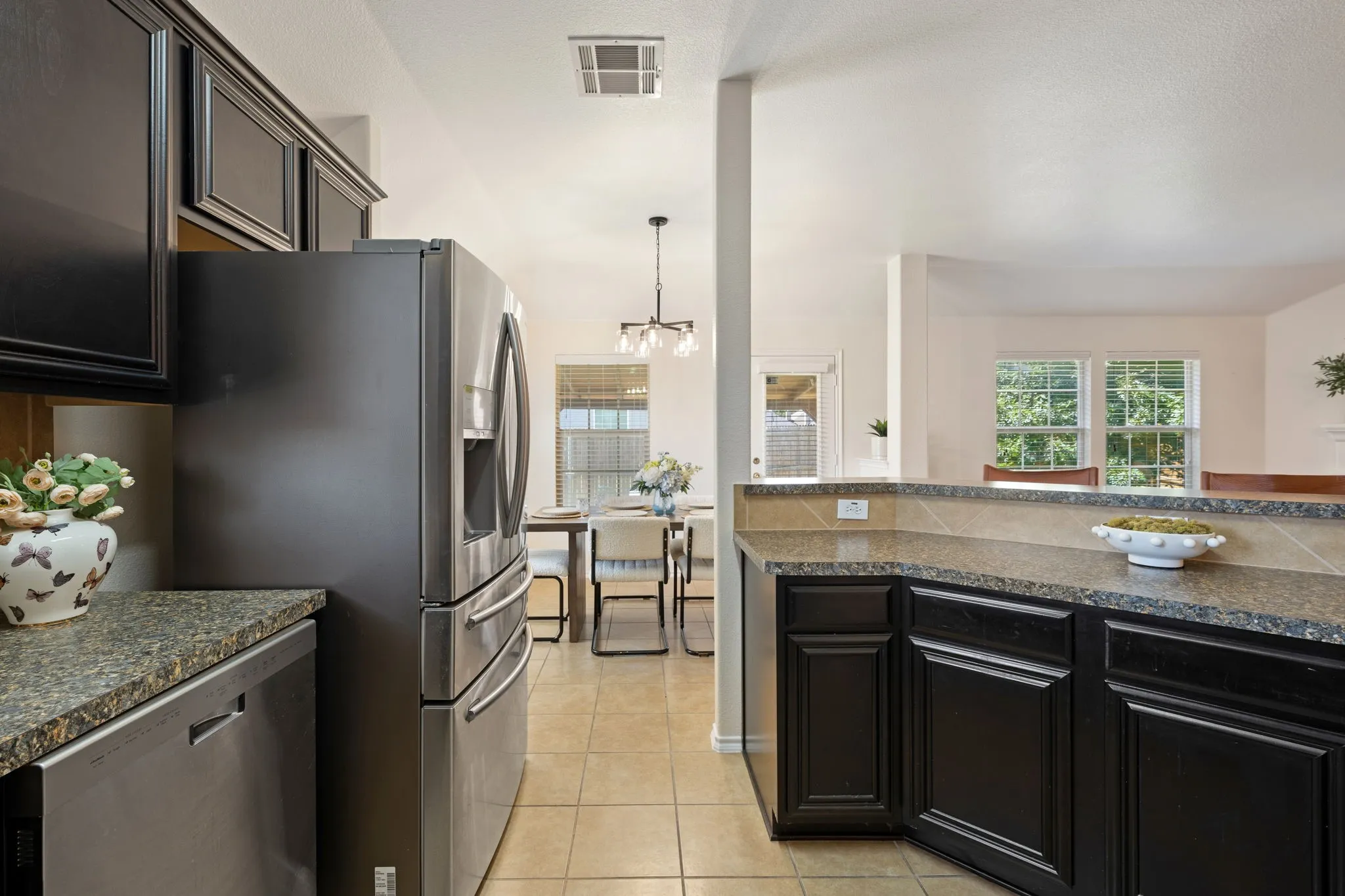 Kitchen featuring dark cabinetry, stainless steel appliances, granite-style countertops, and tile flooring
