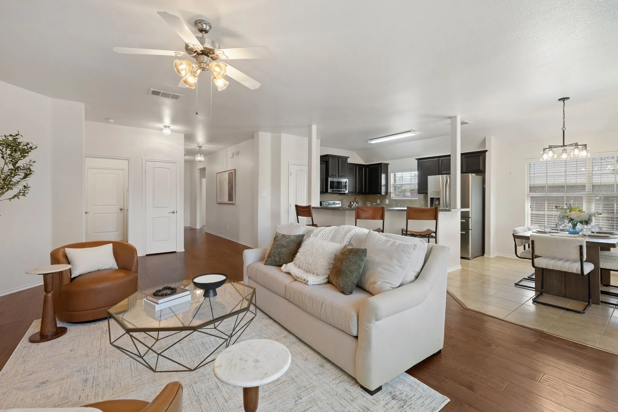 Open-concept living space with wood-finish flooring, a ceiling fan with integrated lighting, and recessed lighting