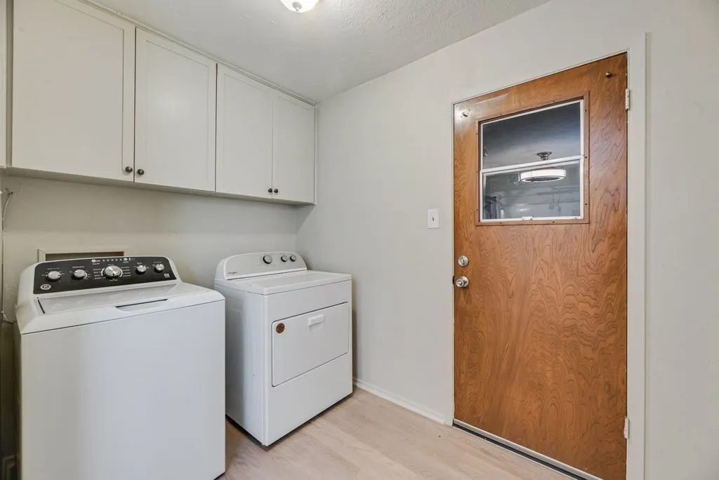 A dedicated laundry room with overhead cabinetry provides convenient storage and direct backyard access. Washer and dryer are negotiable for added move-in convenience.