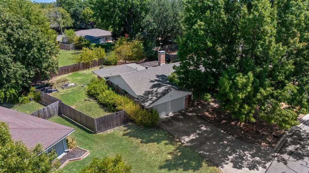 Aerial view highlights the home’s attached 2-car garage, spacious fenced yard and beautiful mature trees, all tucked into an established Denton neighborhood.