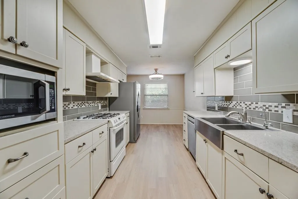 Galley-style kitchen offers abundant cabinetry, granite countertops, stainless steel appliances, a gas range and generous prep space. The kitchen flows into a charming dining area overlooking the backyard, creating an easy everyday gathering space.