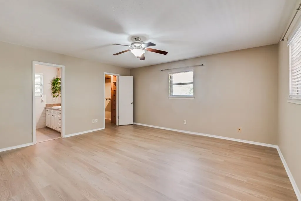Spacious primary suite features brand-new LVP flooring, abundant natural light, a ceiling fan and direct access to the ensuite bath and walk-in closet.