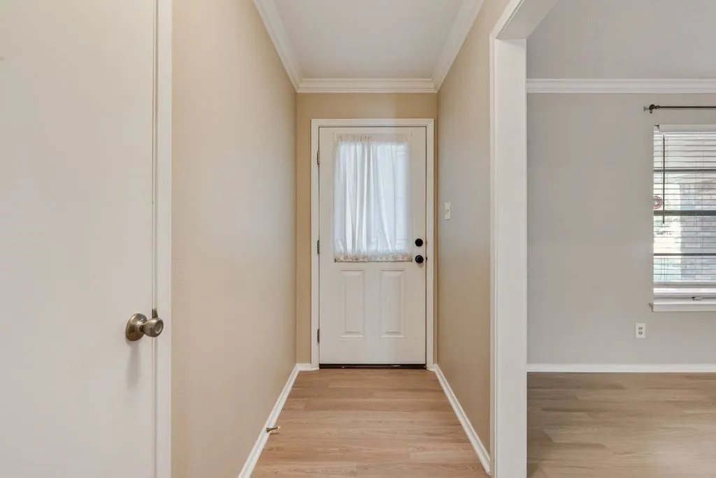 A welcoming entryway opens into the front living space, featuring brand-new LVP flooring, fresh neutral paint and classic crown molding for a clean, move-in-ready first impression.