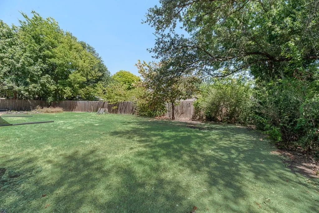 The expansive backyard offers plenty of open green space and mature shade trees, giving you room for pets, play, gardening or future outdoor projects.