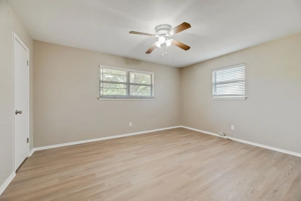 Bedroom 2 offers generous space, brand-new LVP flooring, two windows for natural light and a ceiling fan for added comfort.
