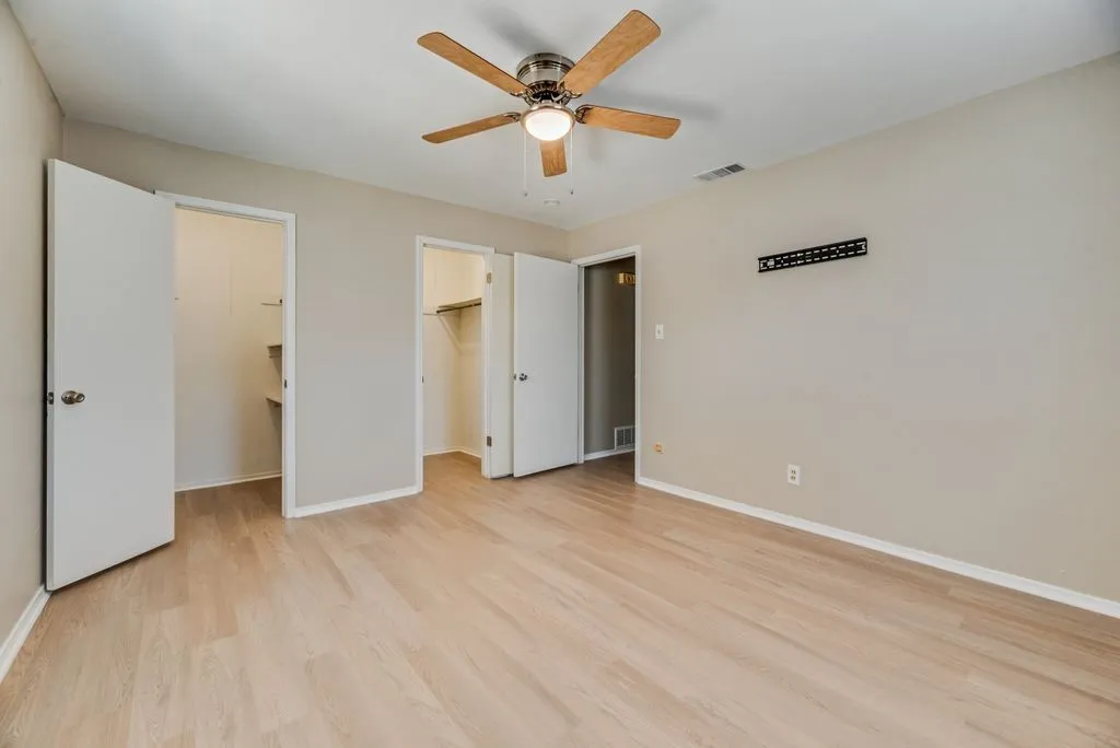 Bedroom 3 offers brand-new LVP flooring, fresh neutral paint, two windows for natural light and a ceiling fan, creating a bright and versatile space.