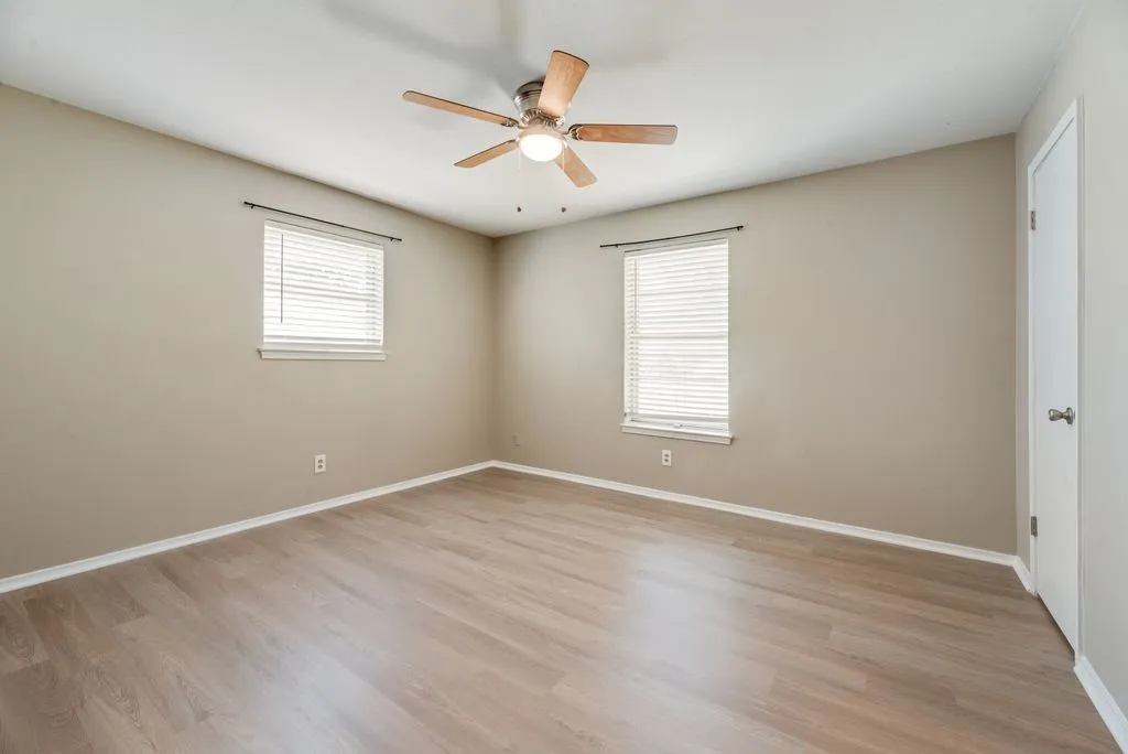 Bedroom 3 offers brand-new LVP flooring, fresh neutral paint, two windows for natural light and a ceiling fan, creating a bright and versatile space.