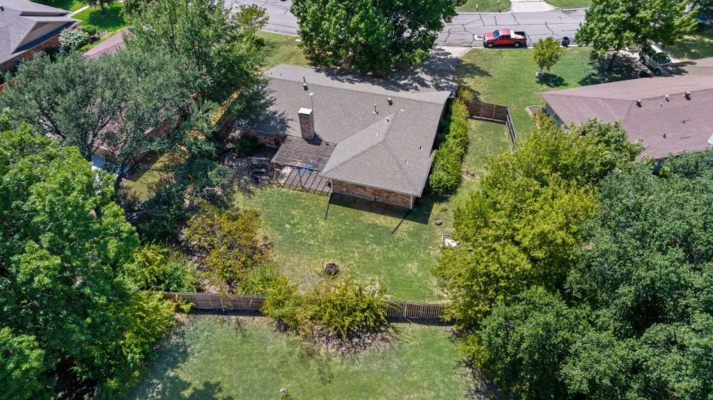 Aerial view showcases the home’s oversized lot of just over one-third acre, with a spacious fenced backyard and mature trees providing shade and privacy.