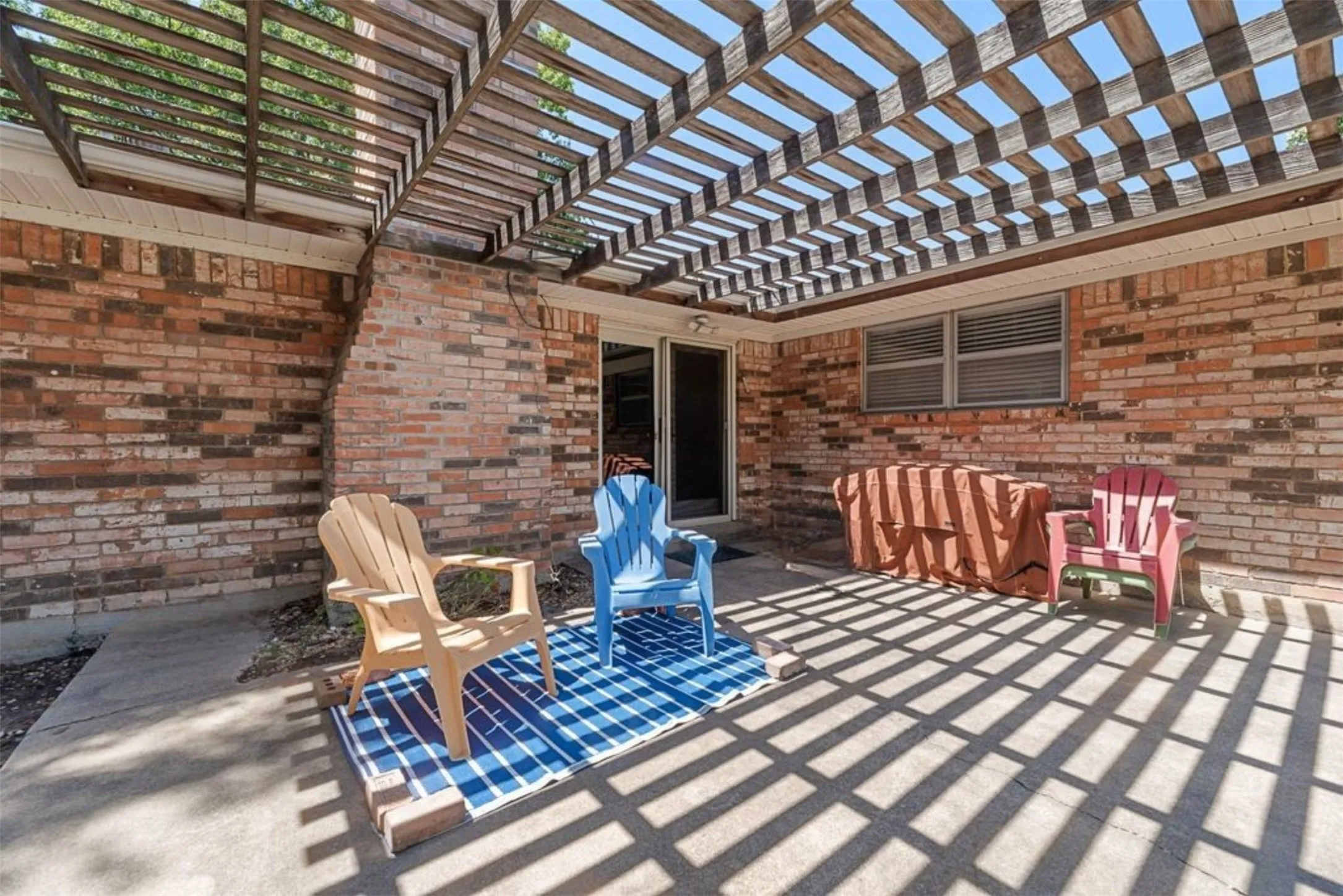 A spacious back patio with an overhead pergola creates a great outdoor living area for relaxing, grilling or entertaining while enjoying the oversized backyard.