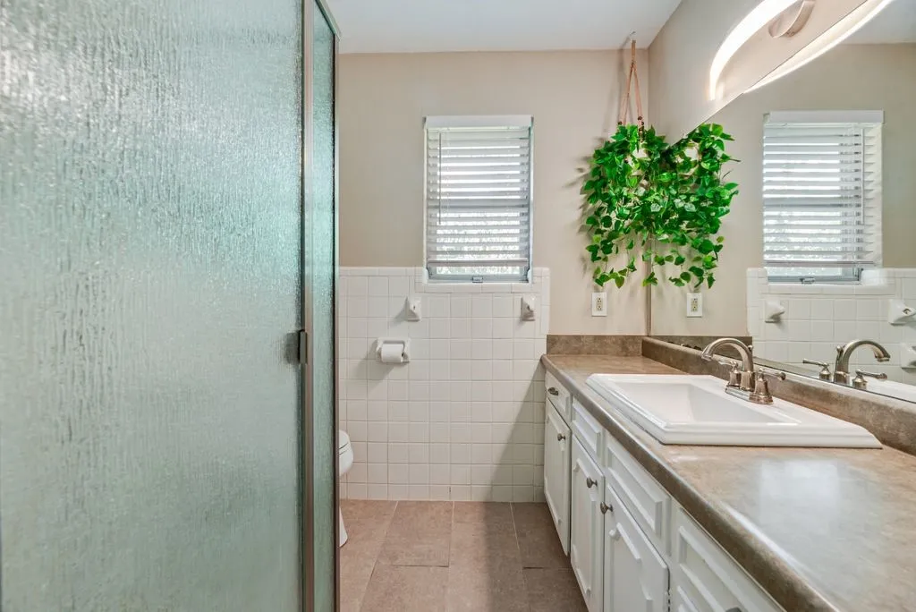 The private ensuite bath features an extended vanity with generous counter space and cabinetry, plus a walk-in shower and natural light.
