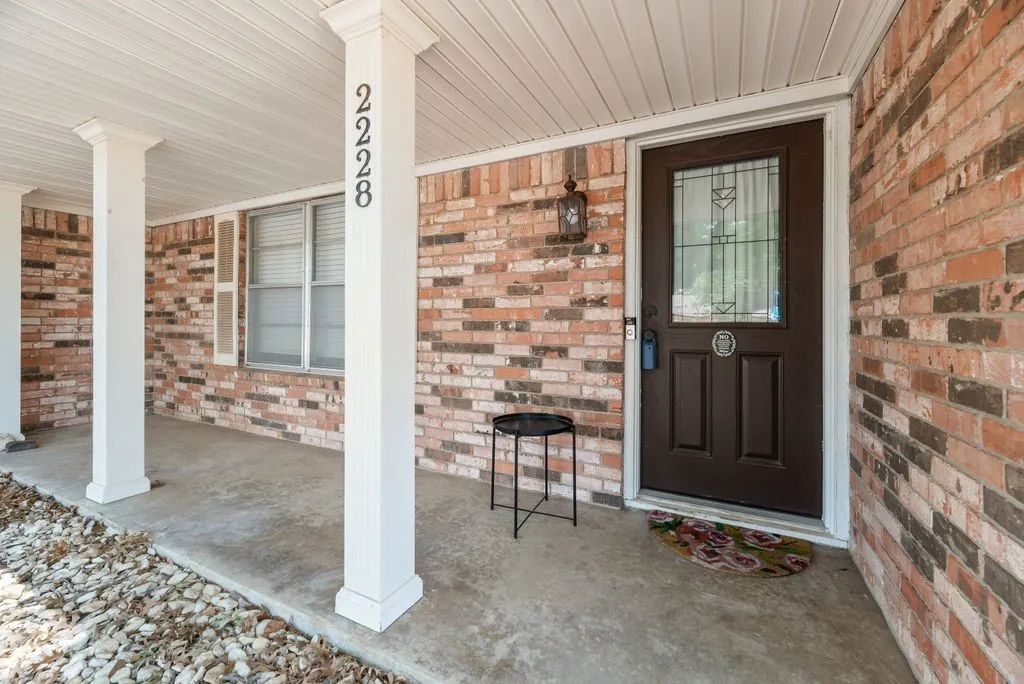 A welcoming covered front porch adds charm and character to this classic brick home, offering a shaded spot to greet guests or add your favorite seasonal décor.