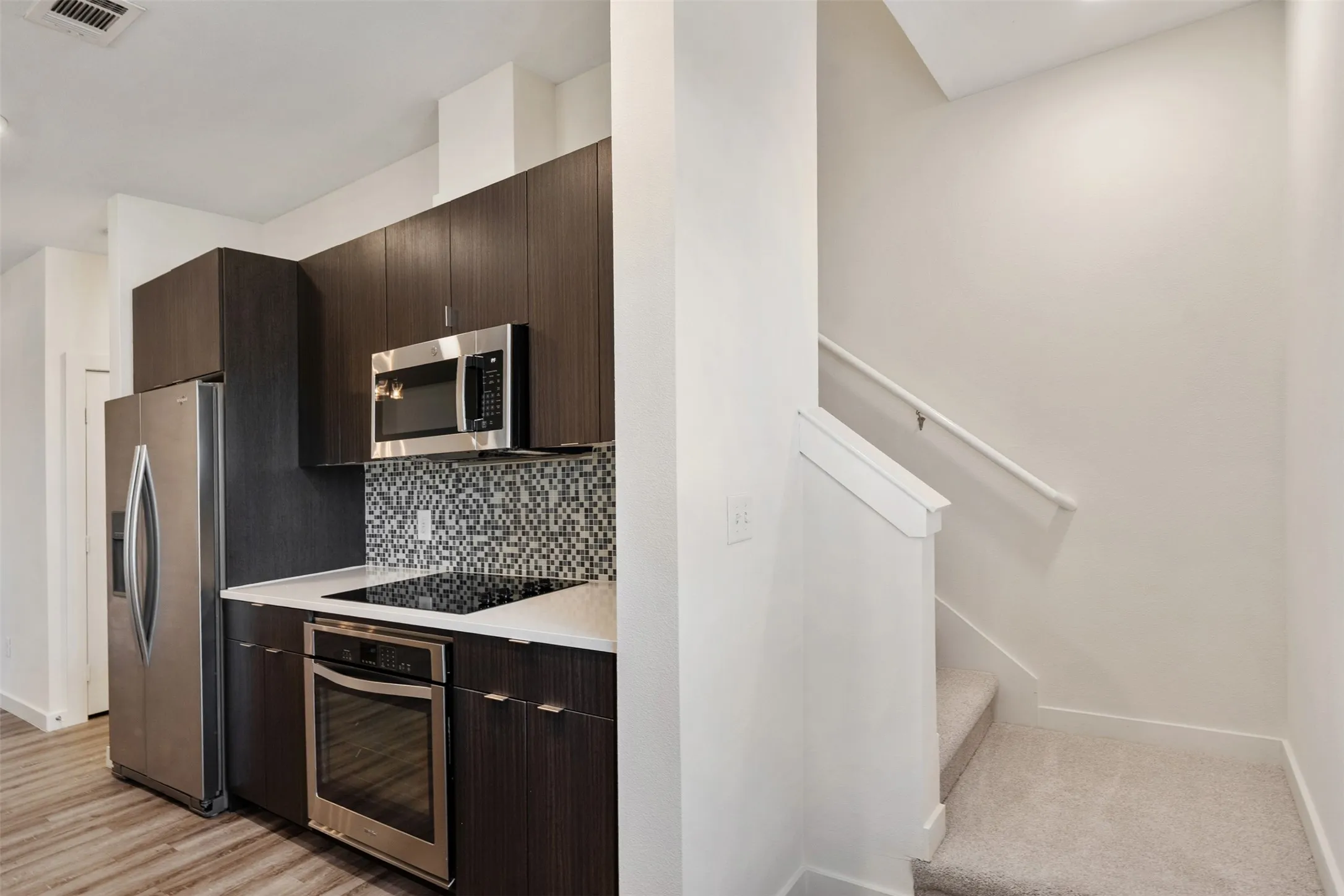 Kitchen with wood-finish cabinetry, stainless steel appliances, and mosaic tile backsplash