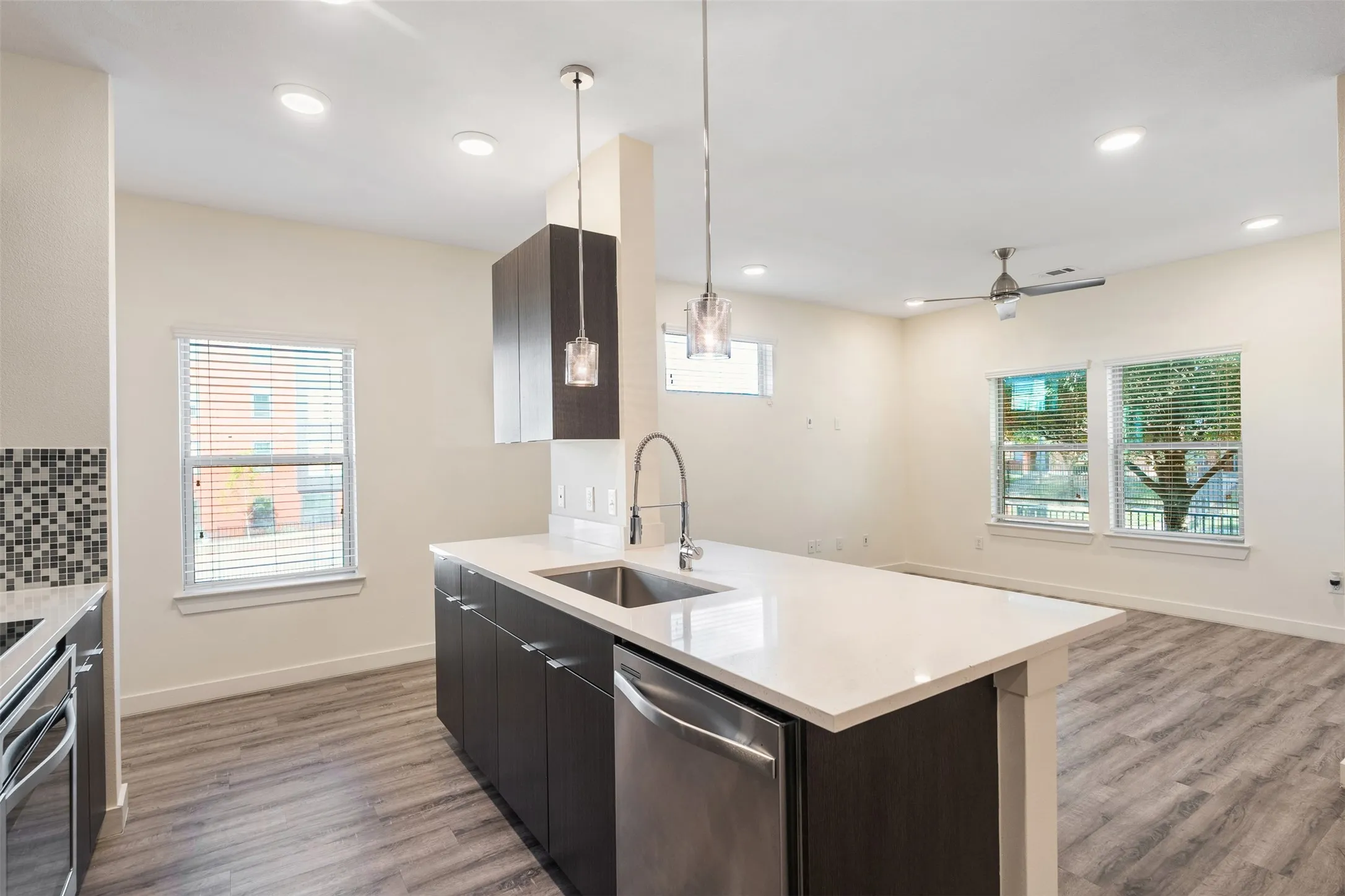 Open-concept kitchen with a large island, wood-finish flooring, recessed lighting, and stainless steel appliances