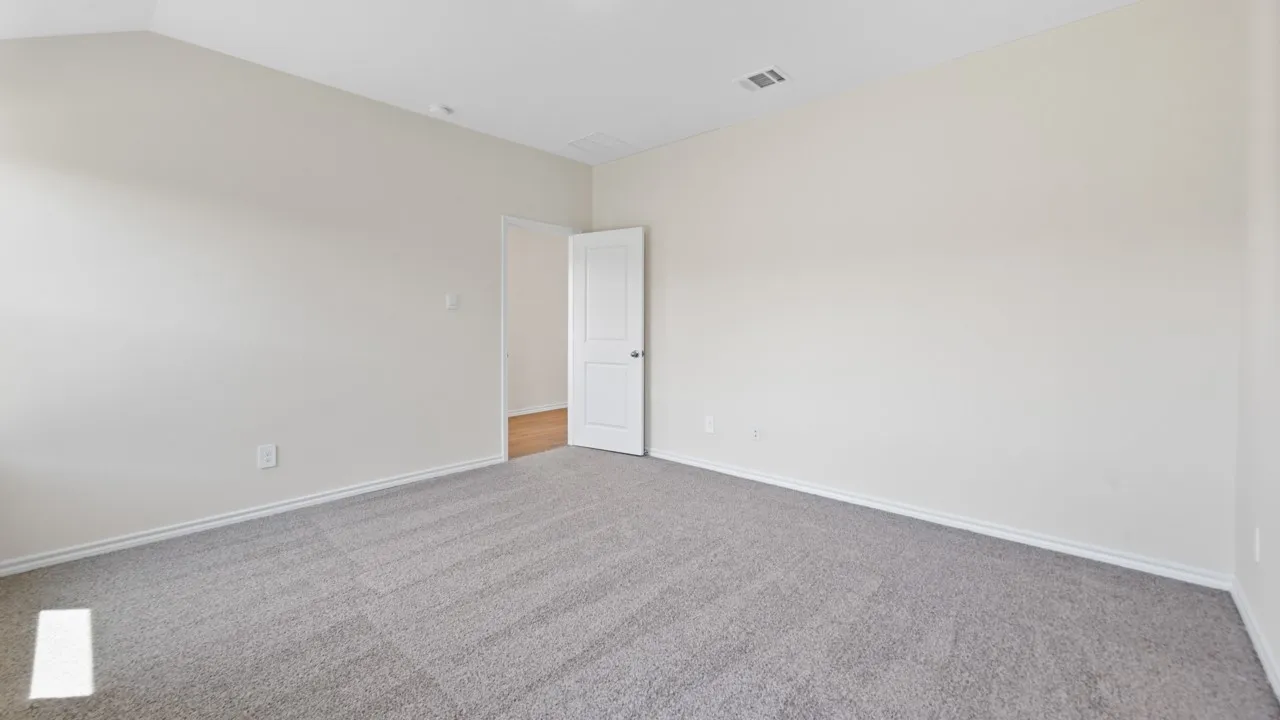 Spacious interior room with light neutral wall paint and plush grey carpeting