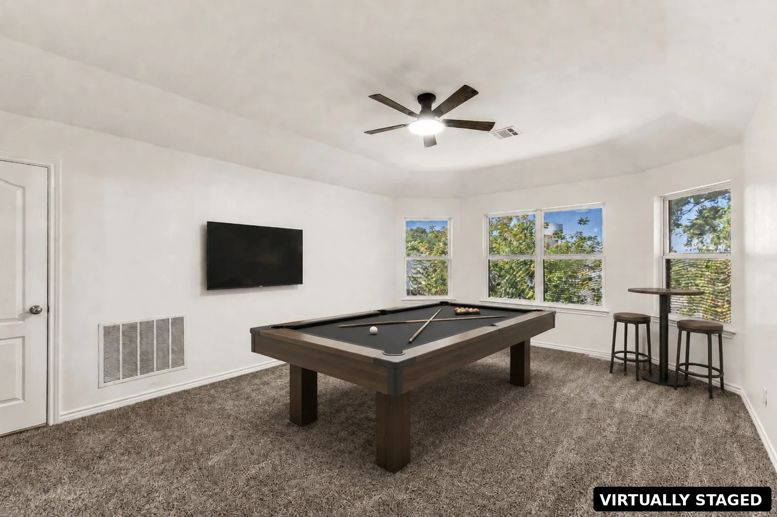 Bright room with textured carpeting, multiple windows, and a ceiling fan