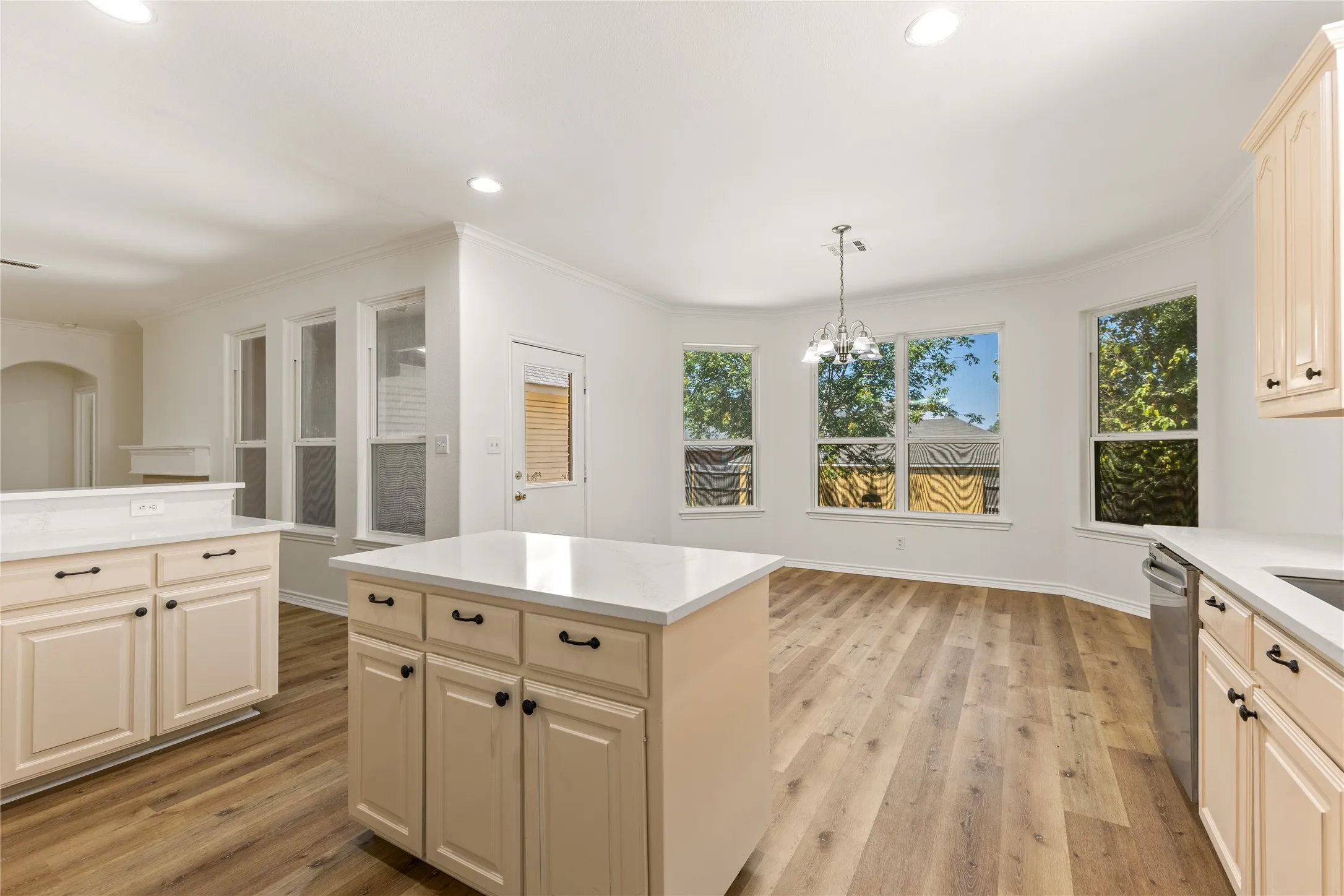 Kitchen featuring wood-finish flooring, light cabinetry, white countertops, recessed lighting, and a kitchen island with storage