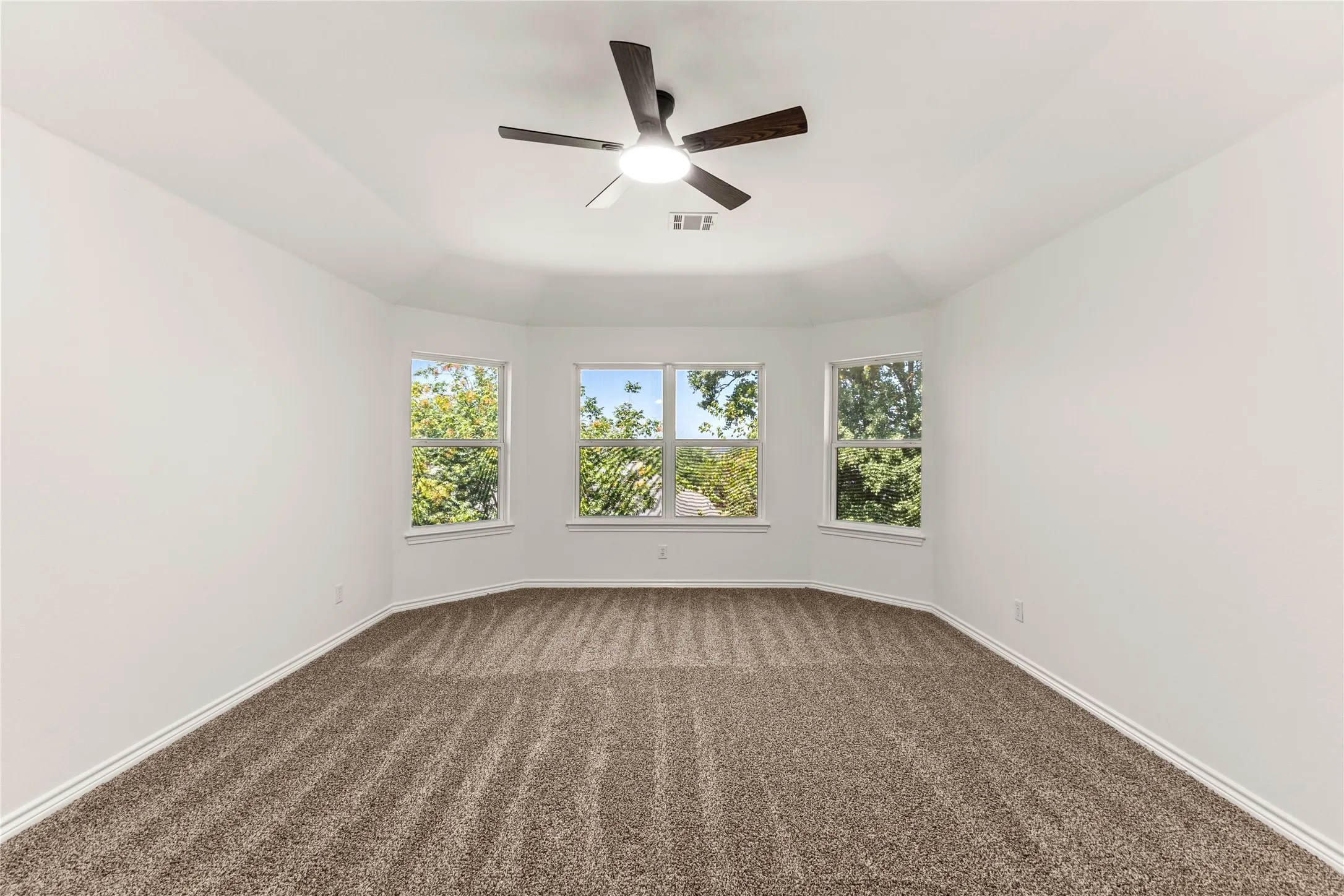 Tray ceiling with integrated lighting, ceiling fan, carpeting, and three transom windows