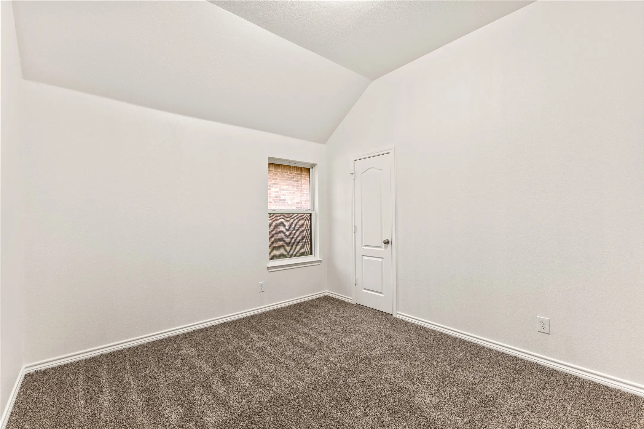 Vaulted ceiling with neutral paint finishes, single window, and plush carpeting