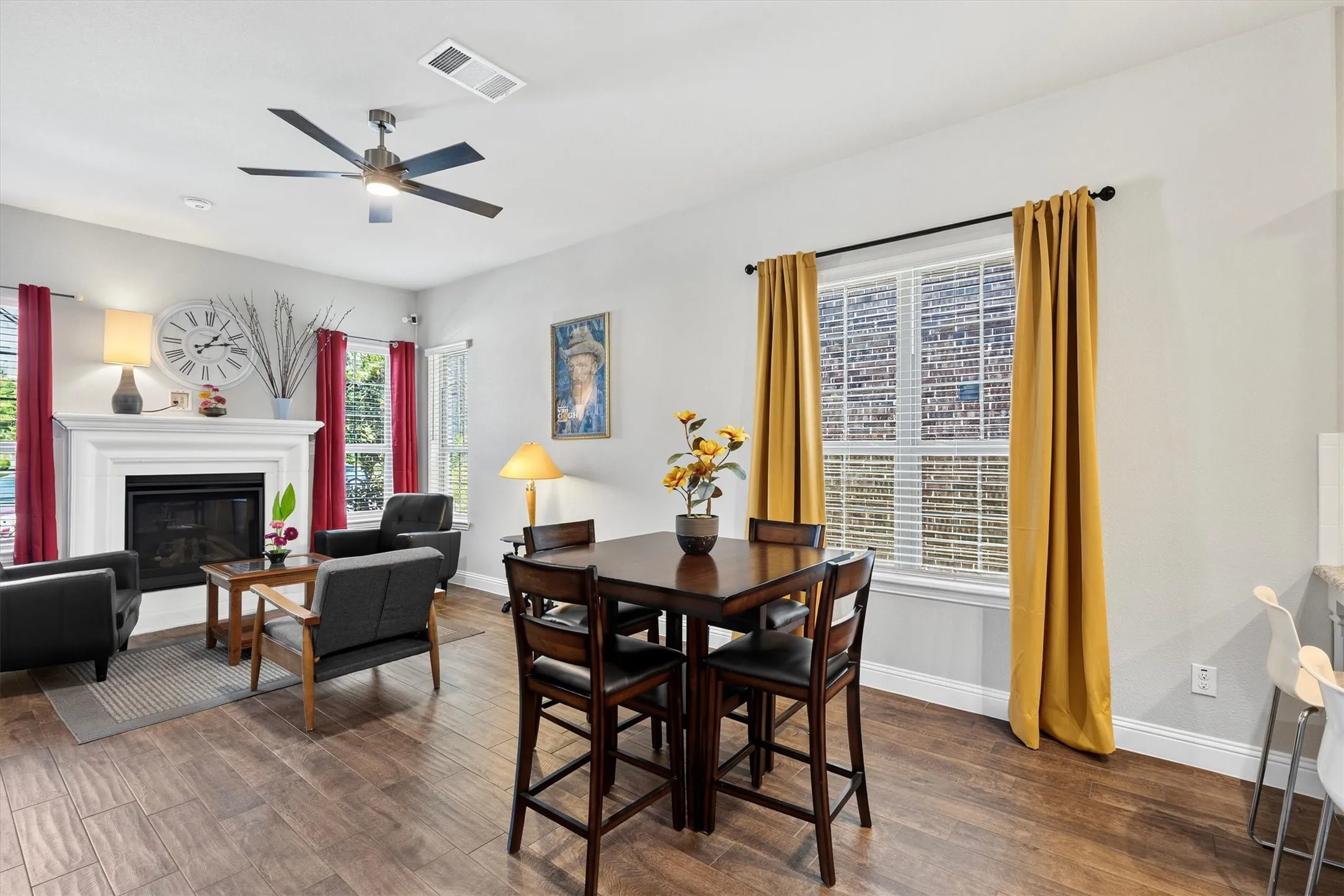 Living area with wood-finish flooring, a ceiling fan, and a fireplace with a white​​‌​​​​‌​​‌‌​‌‌​​​‌‌​‌​‌​‌​​​‌​​ mantel