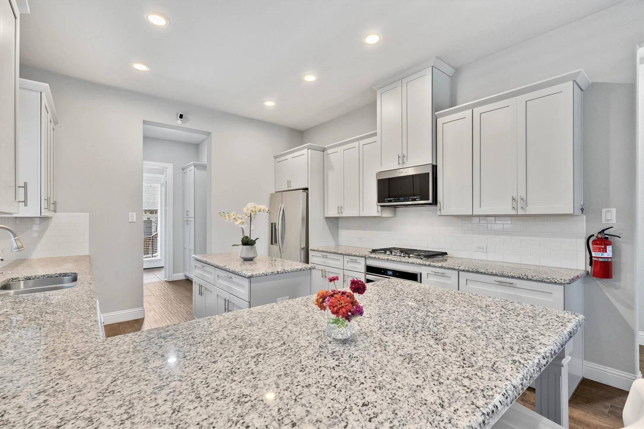Contemporary kitchen featuring white cabinetry, light-toned countertops, stainless steel appliances, a white subway tile backsplash, and recessed lighting