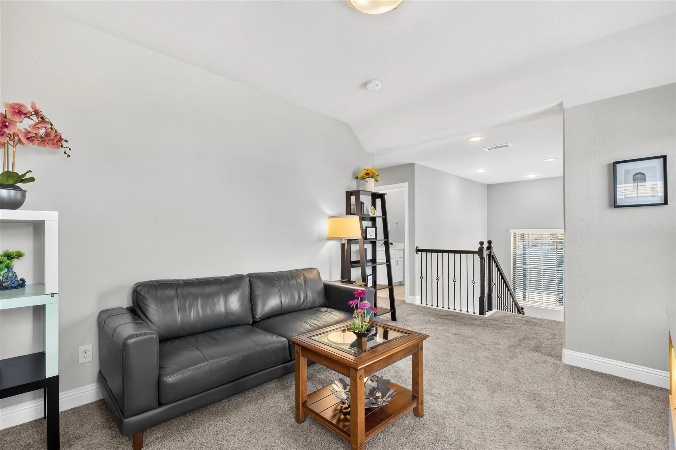 Carpeted landing with a decorative iron railing and recessed lighting