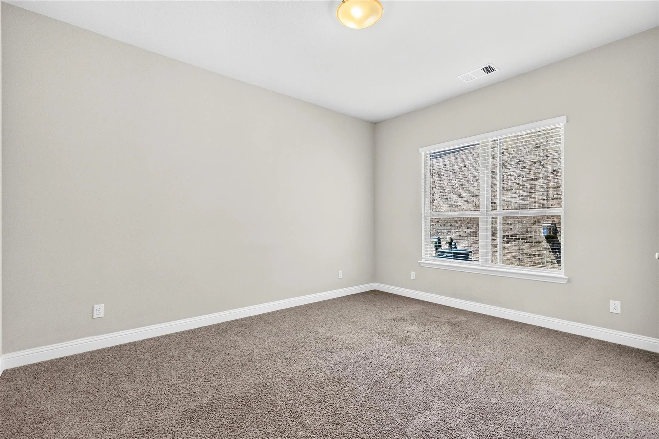 Neutral painted walls, wall-to-wall carpeting, and a window with blinds