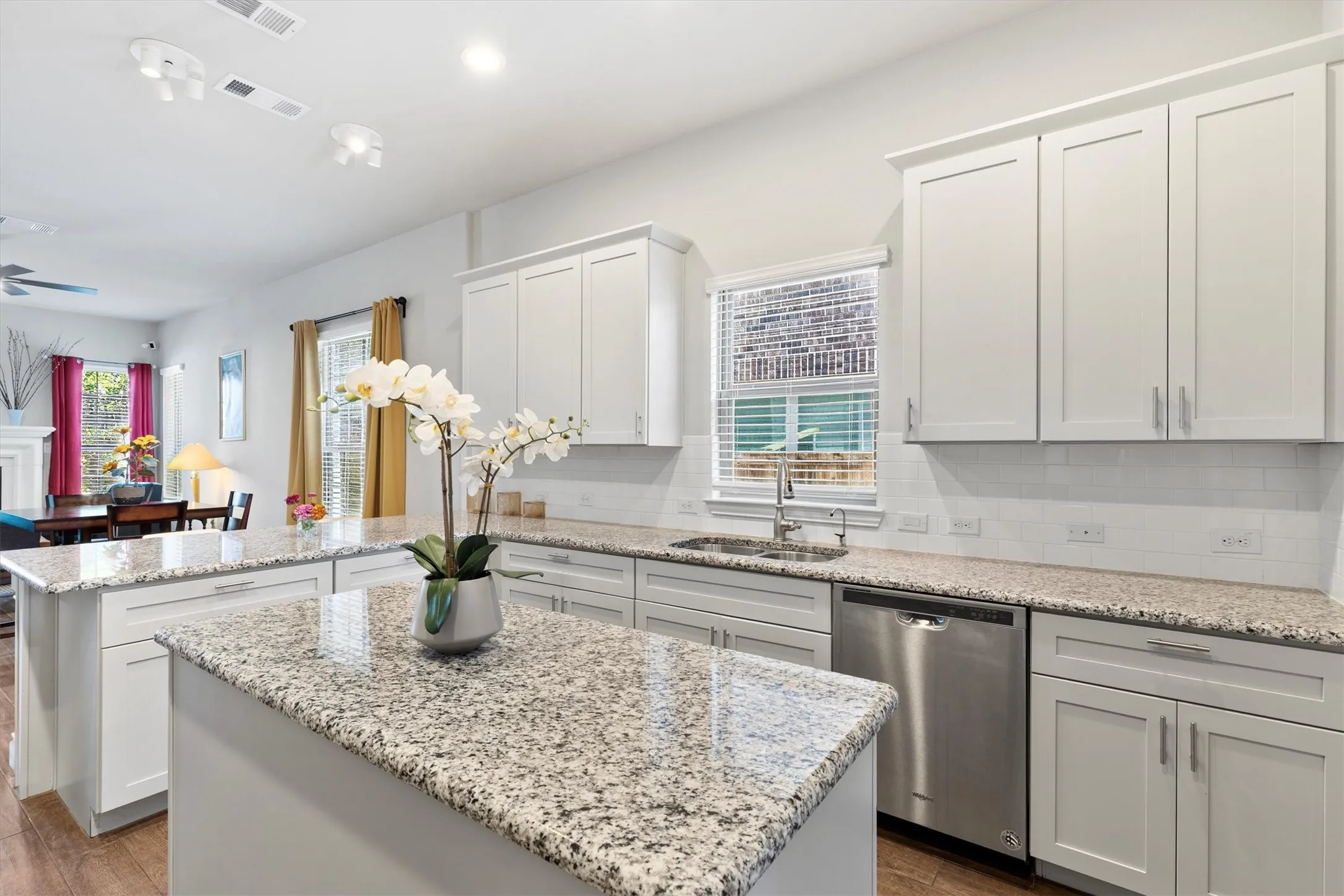 Kitchen featuring white shaker-style cabinetry, granite countertops, stainless steel dishwasher, and an undermount sink