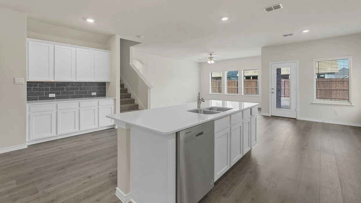 Spacious kitchen island with an undermount double sink, stainless steel dishwasher, and white cabinetry
