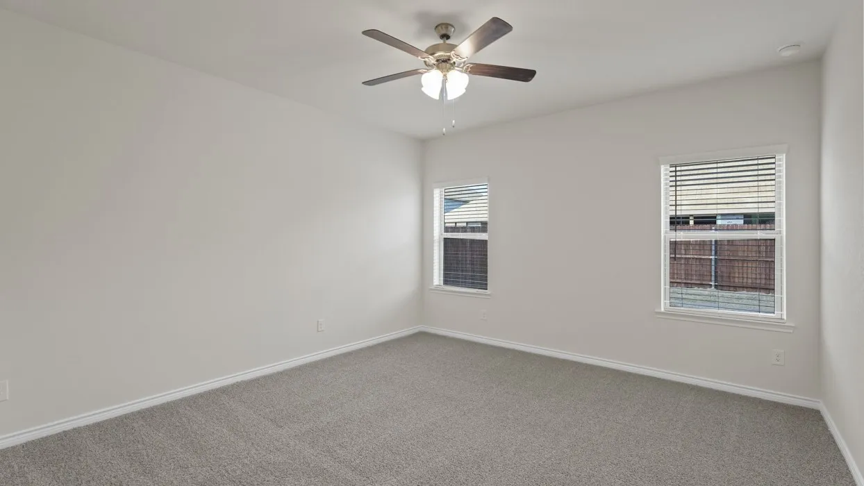 Light gray carpeting, white walls, two windows with blinds, and a ceiling fan with integrated lighting