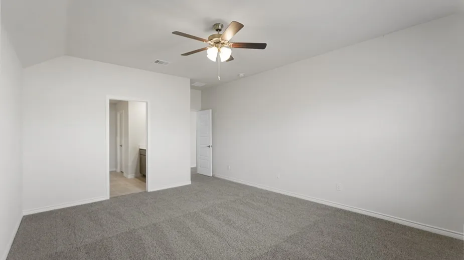Spacious room with vaulted ceiling, plush carpet flooring, and a ceiling fan with light fixture