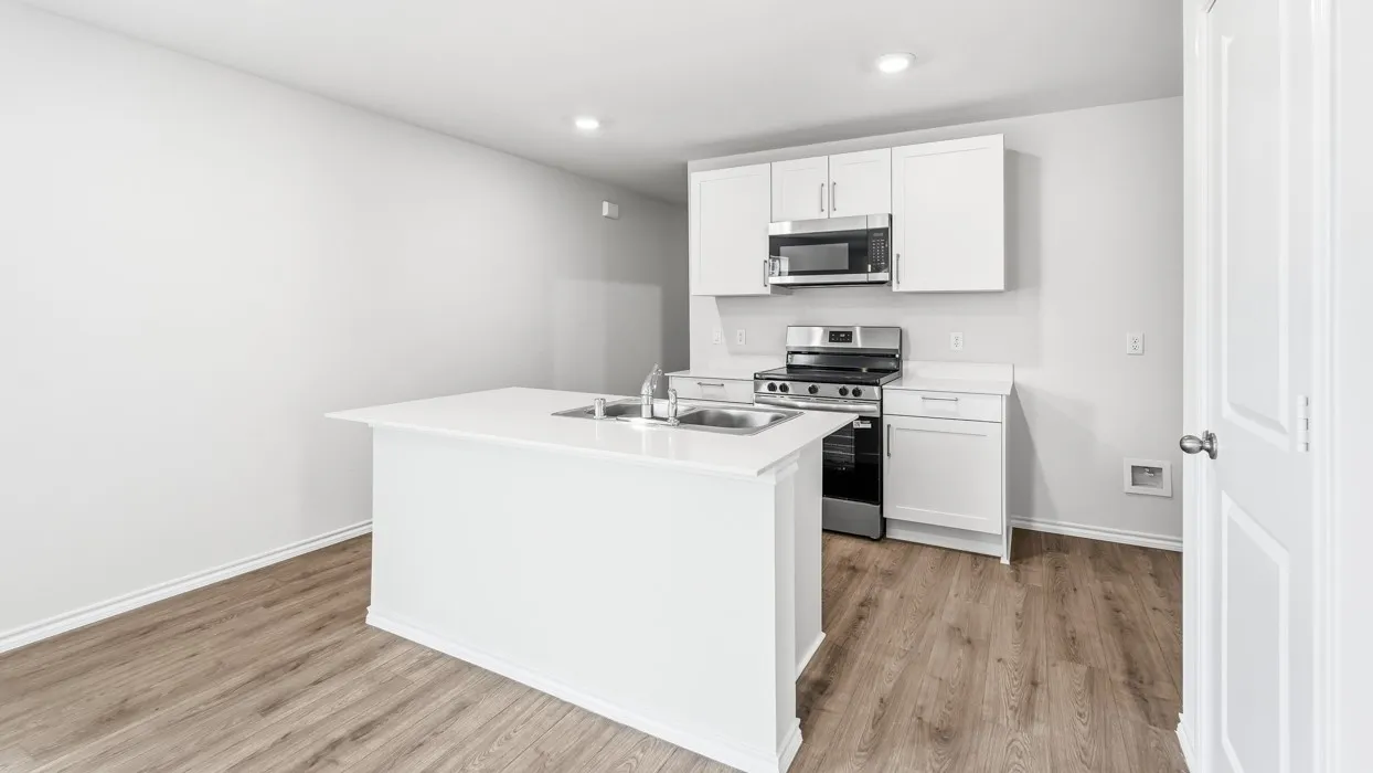 Kitchen featuring white shaker cabinetry, stainless steel appliances, a center island with an undermount double basin sink, and wood-finish flooring
