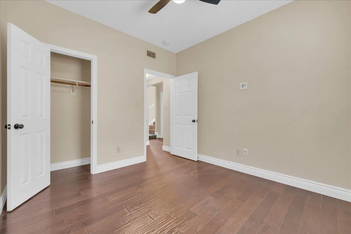 Wood-finish flooring throughout, white trim, and a ceiling fan