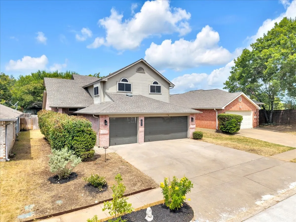 Two-story exterior with a two-car attached garage, a separate single-car garage, and brick accents
